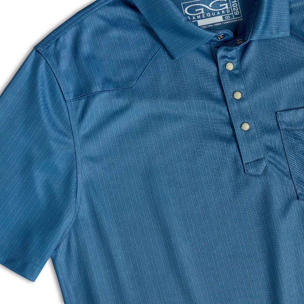 Close-up of a blue short-sleeve polo shirt with a subtle vertical stripe texture, featuring a three-button placket and a chest pocket. The G-Game logo is visible on the inner neck label.