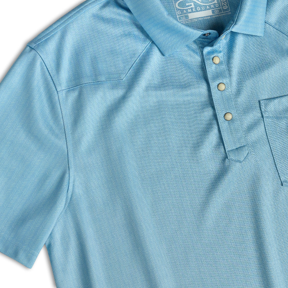 A close-up of a light blue short-sleeve polo shirt with a three-button placket and a chest pocket, showing the fabric texture and collar label.