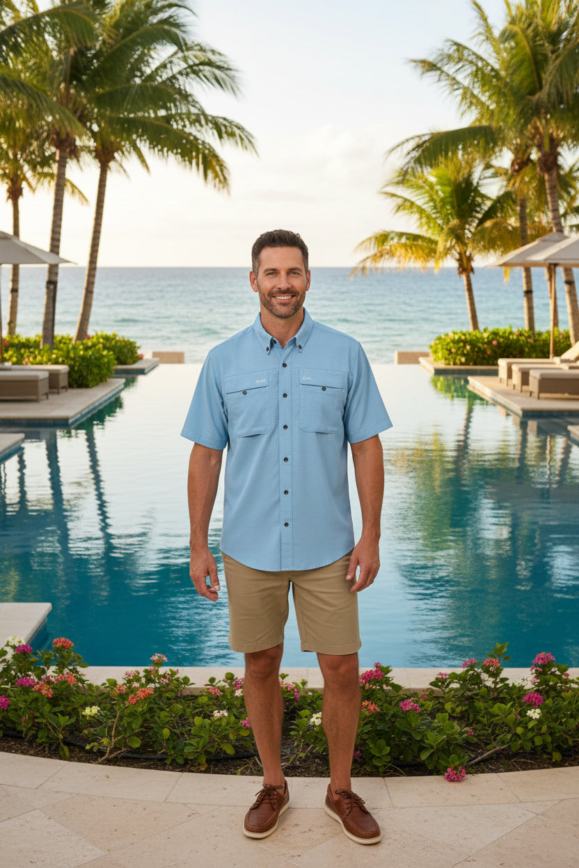 A light blue short-sleeve button-up shirt with two chest pockets and a small embroidered logo on the left chest, displayed flat against a white background.