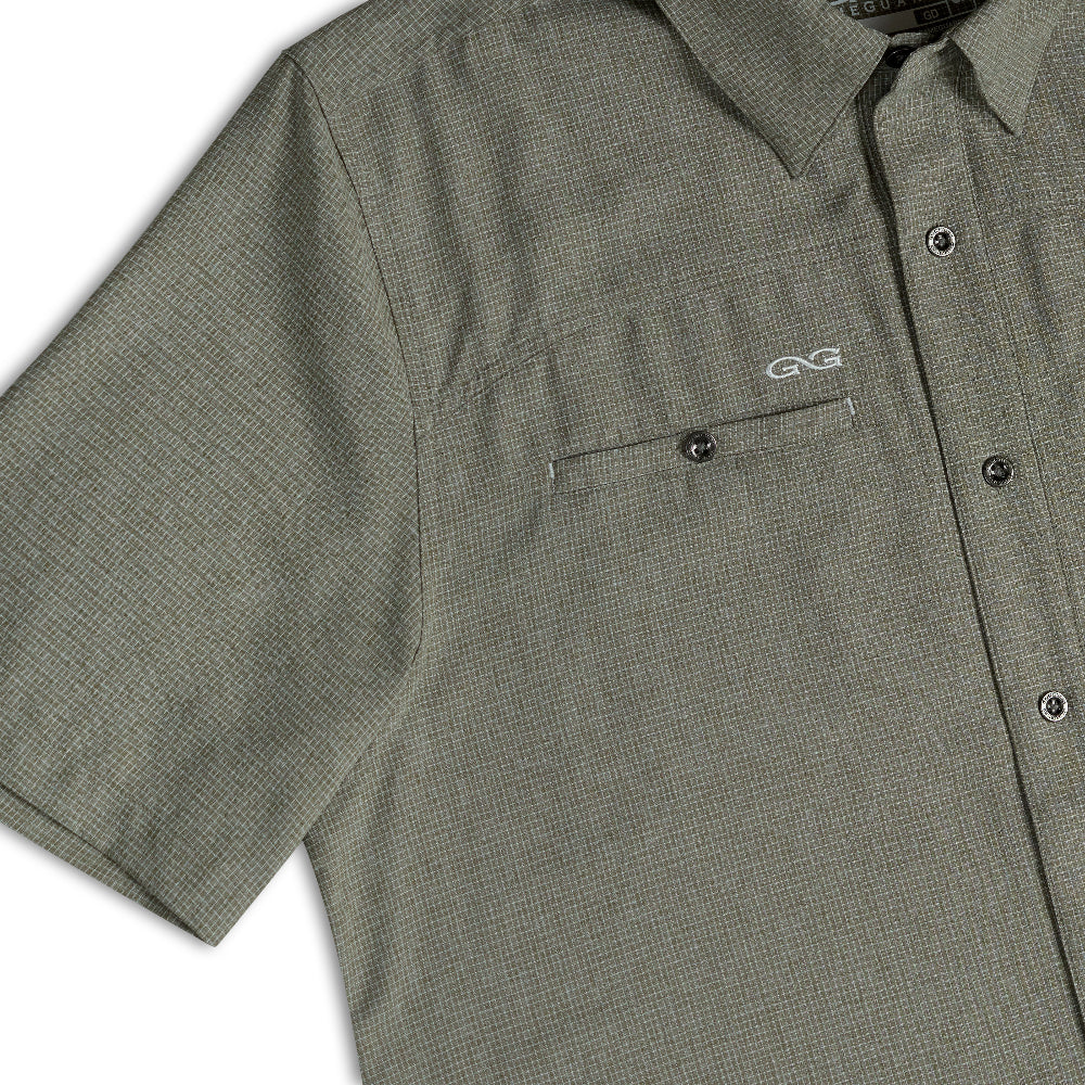 Close-up of a short-sleeve button-up shirt in a textured olive green and black micro-check pattern, featuring a chest pocket with a white embroidered GG logo.