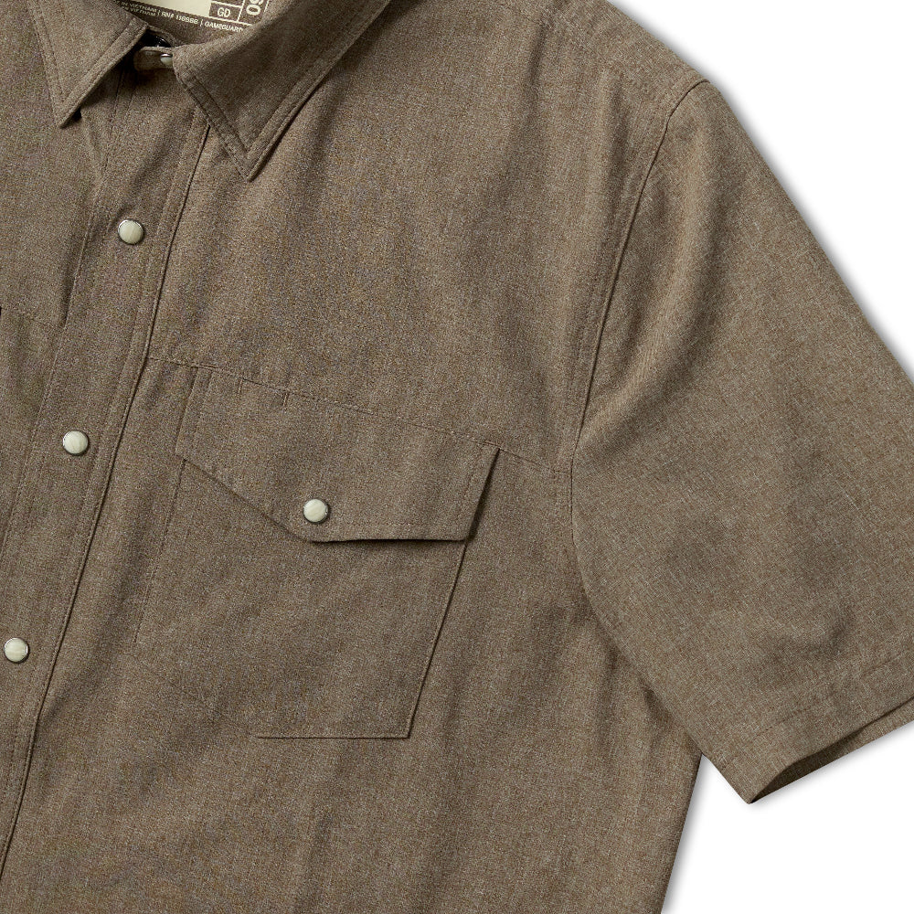 Close-up of a short-sleeve button-up shirt in a muted taupe-brown fabric, showing part of the chest pocket and front buttons.