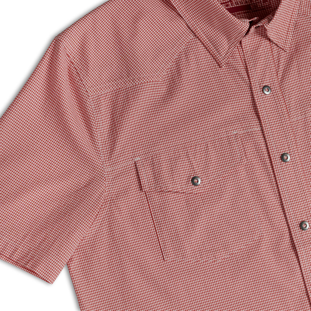 A close-up of a short-sleeve button-up shirt in a dusty rose or muted pink color, showing a chest pocket and snap-button closure.