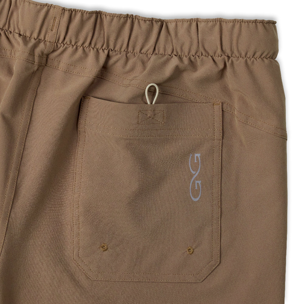 Close-up of a pair of brown drawstring pants showing an elastic waistband and a front pocket with a small embroidered logo.