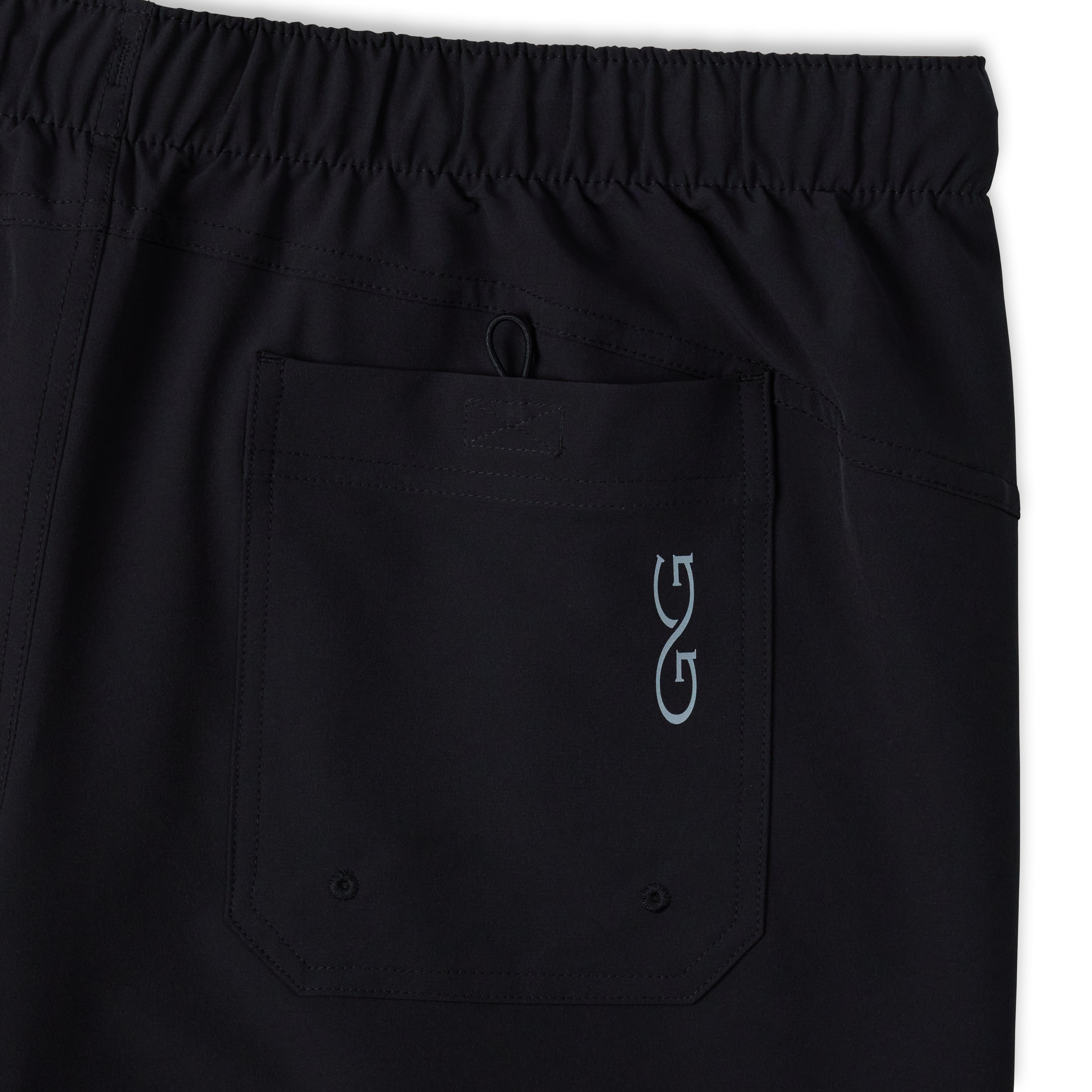 Close-up of black drawstring shorts showing an elastic waistband and a front pocket with a light blue embroidered stylized 'G' logo on the left side.