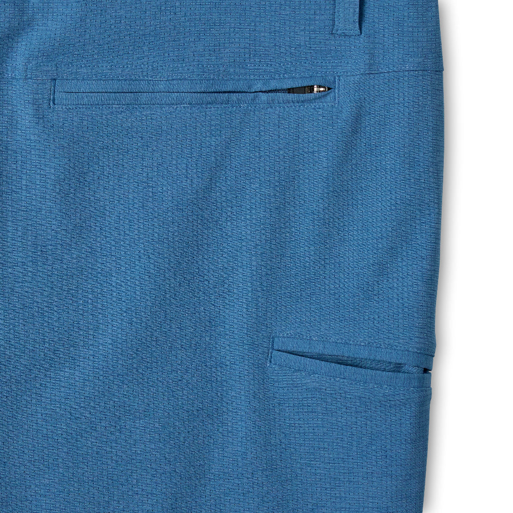 Close-up of blue textured fabric showing a side pocket with a pen tucked into the opening, photographed against a white background.