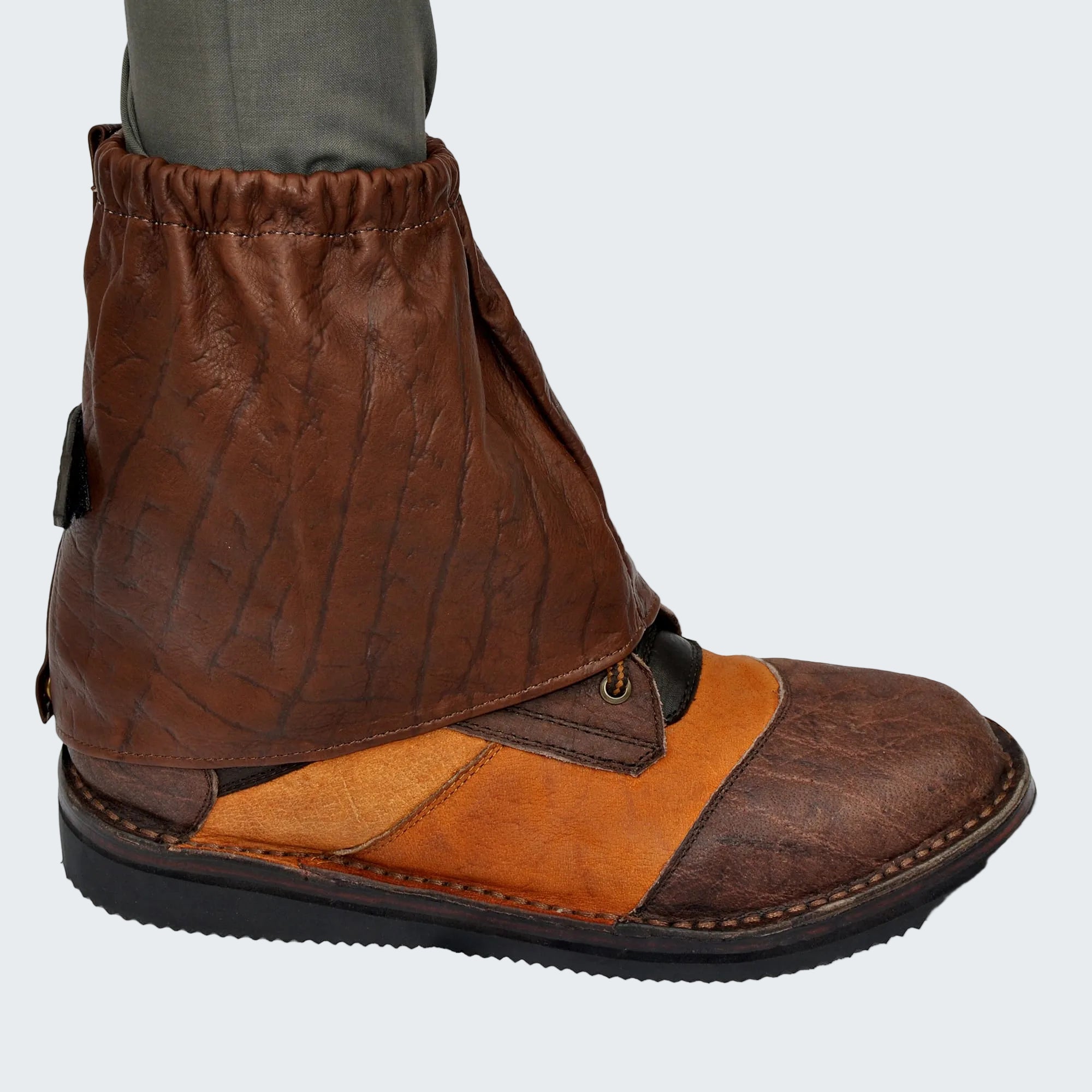Brown leather gaiter over a boot on a white background