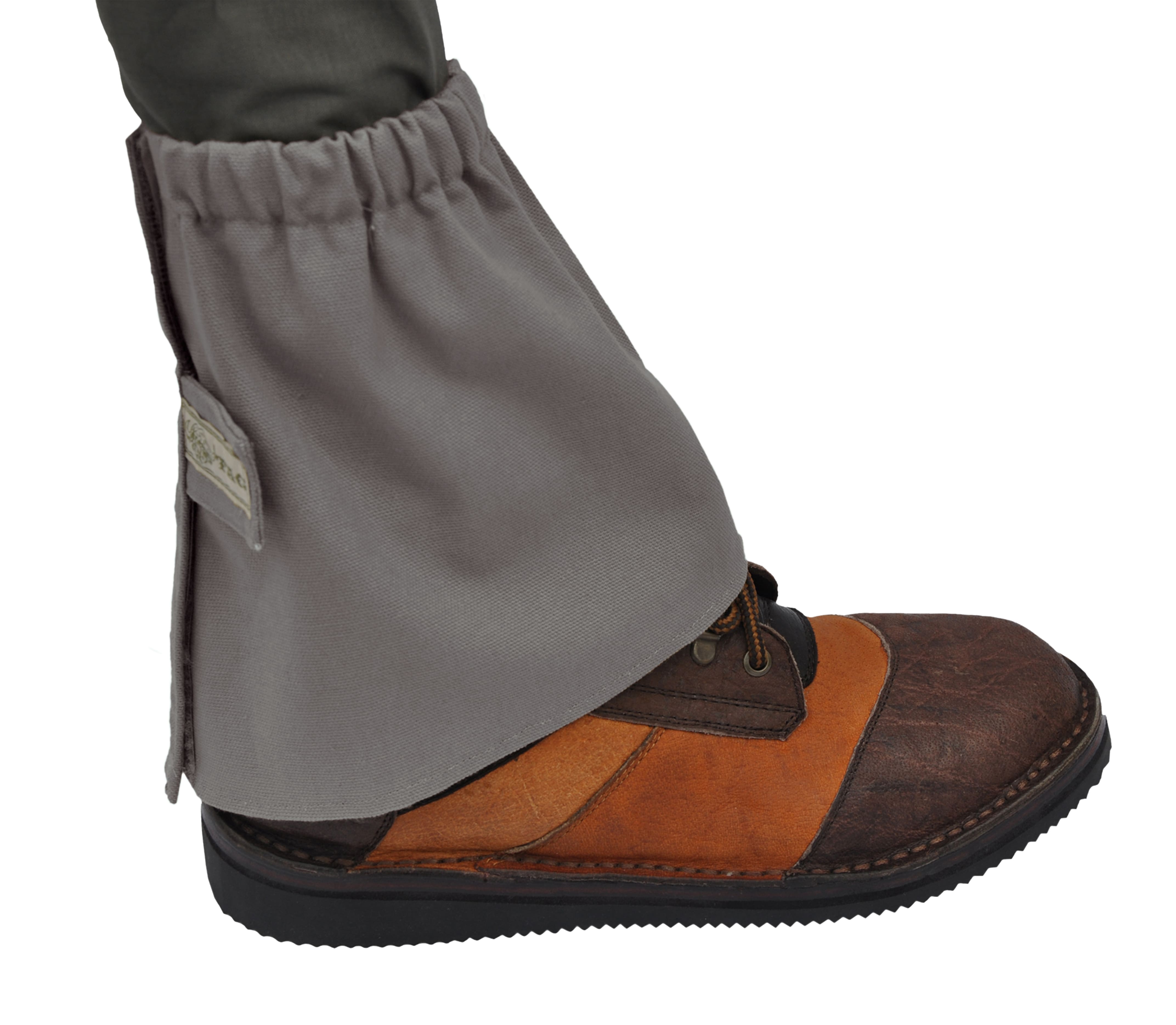 Gray gaiter over a brown and black boot on a white background