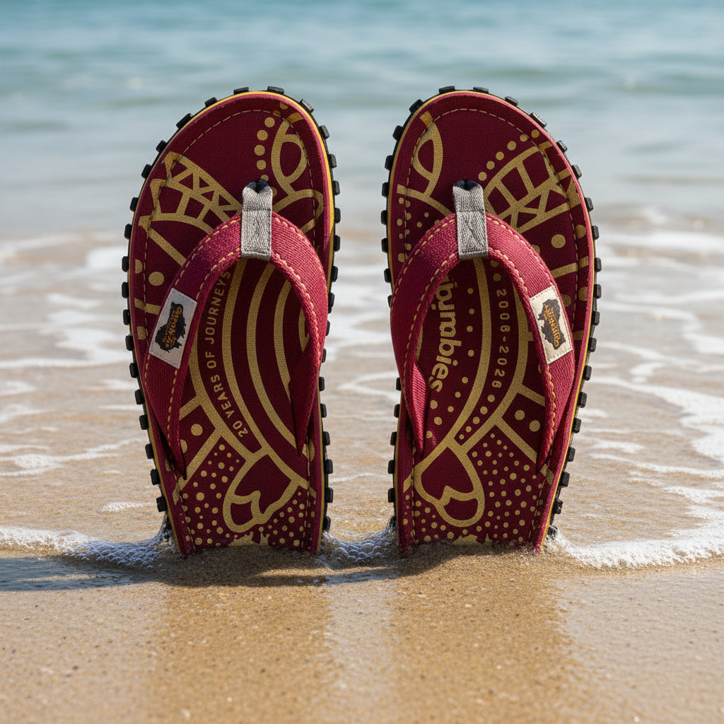 Pair of maroon sandals with gold patterns and 'Gumbies' branding on a white background