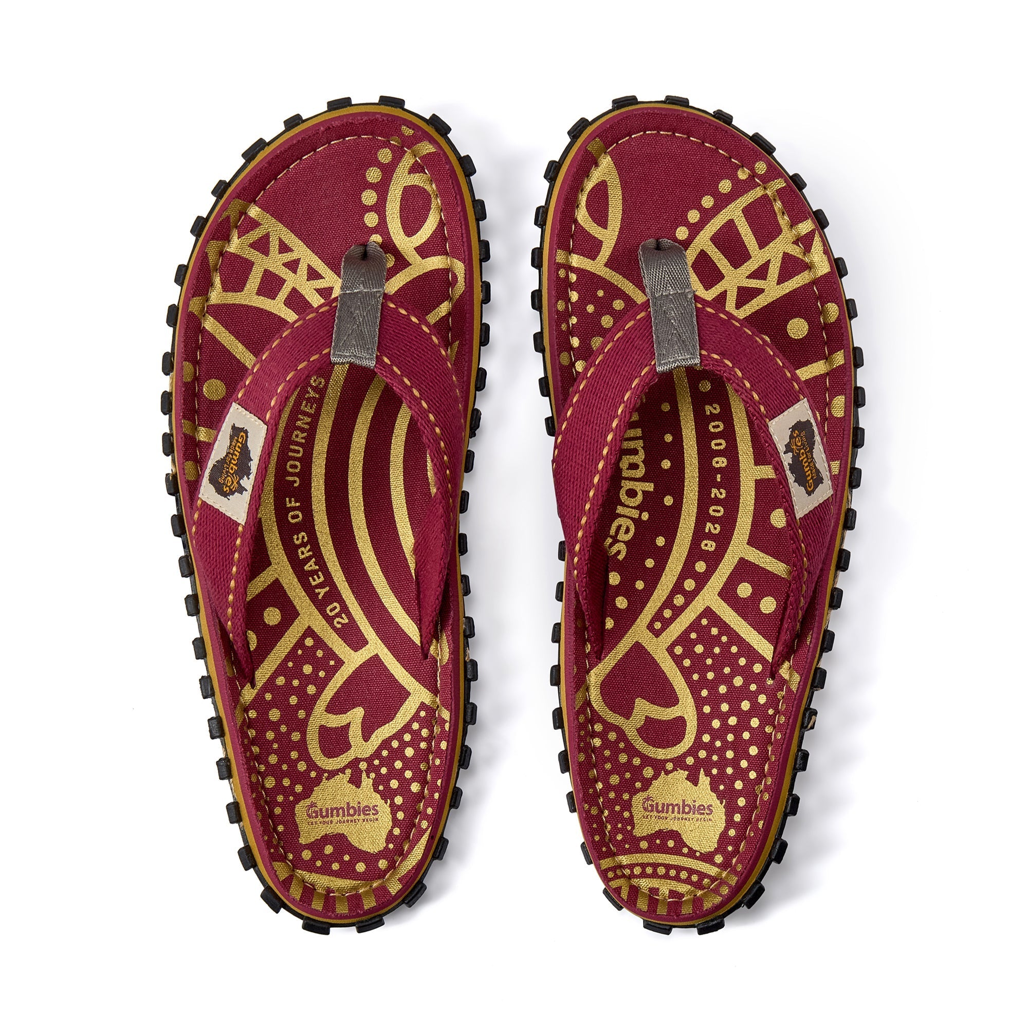 Pair of maroon sandals with gold patterns and 'Gumbies' branding on a white background