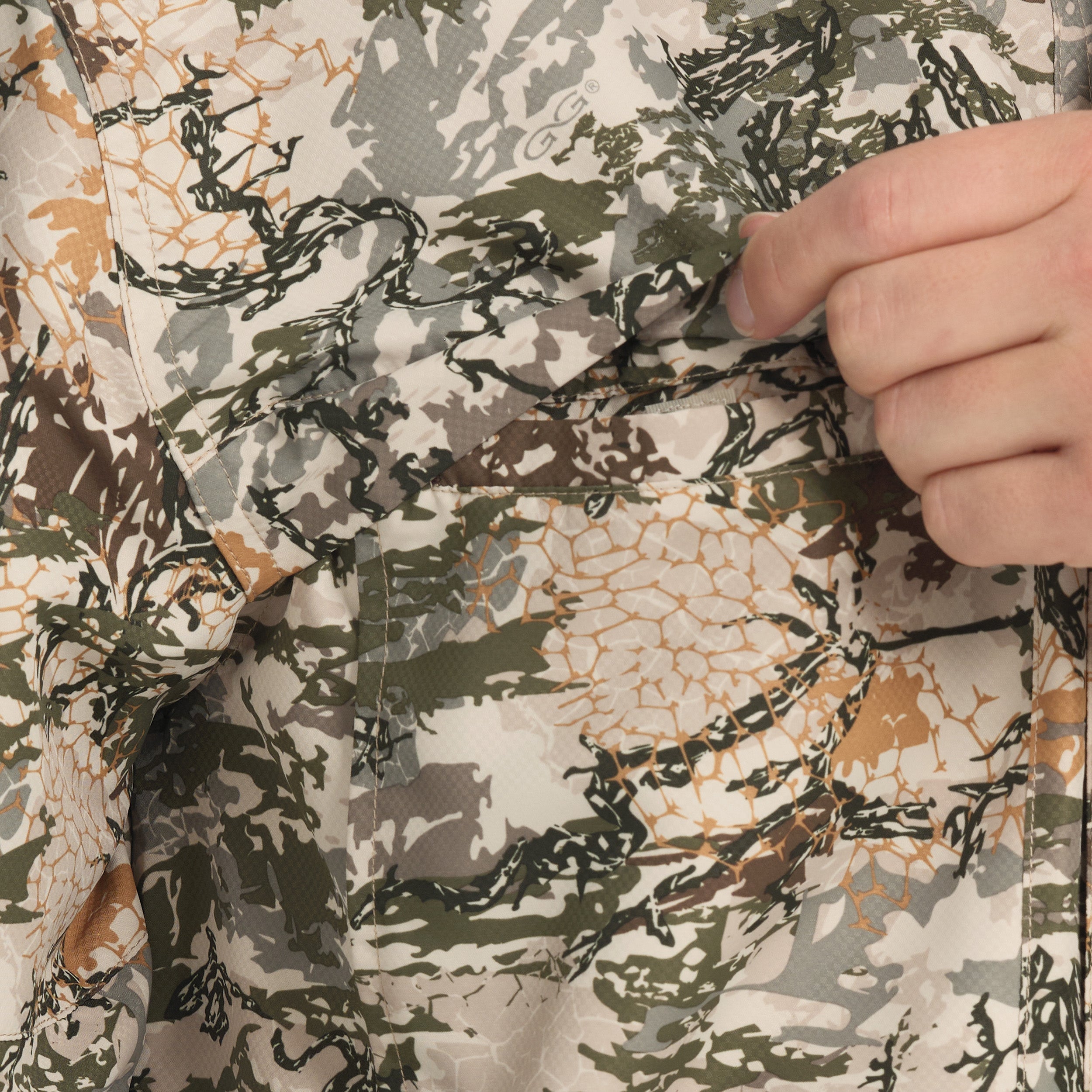 Close-up of camouflage fabric with a hand pointing to it