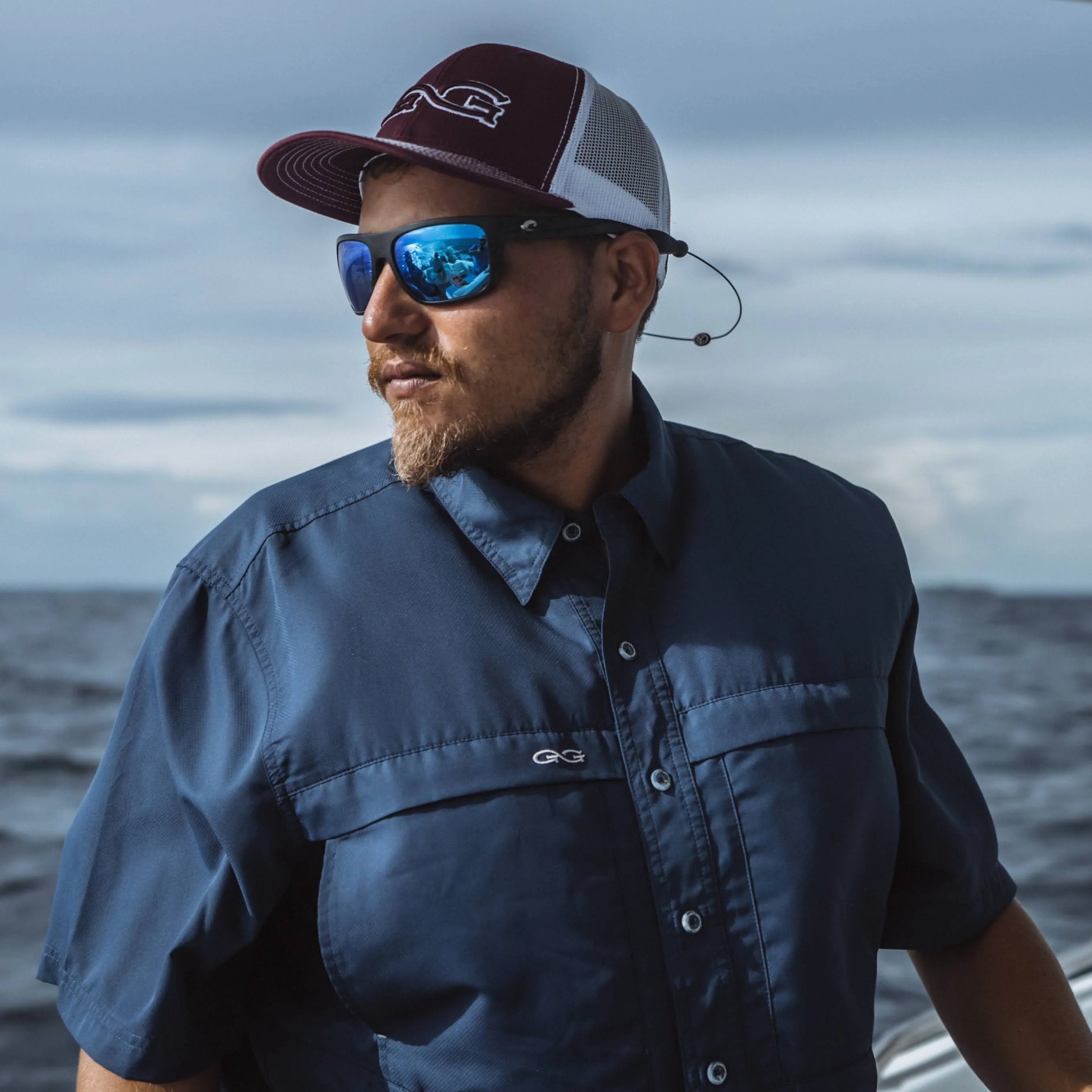 Man wearing a cap and sunglasses with a blurred ocean background