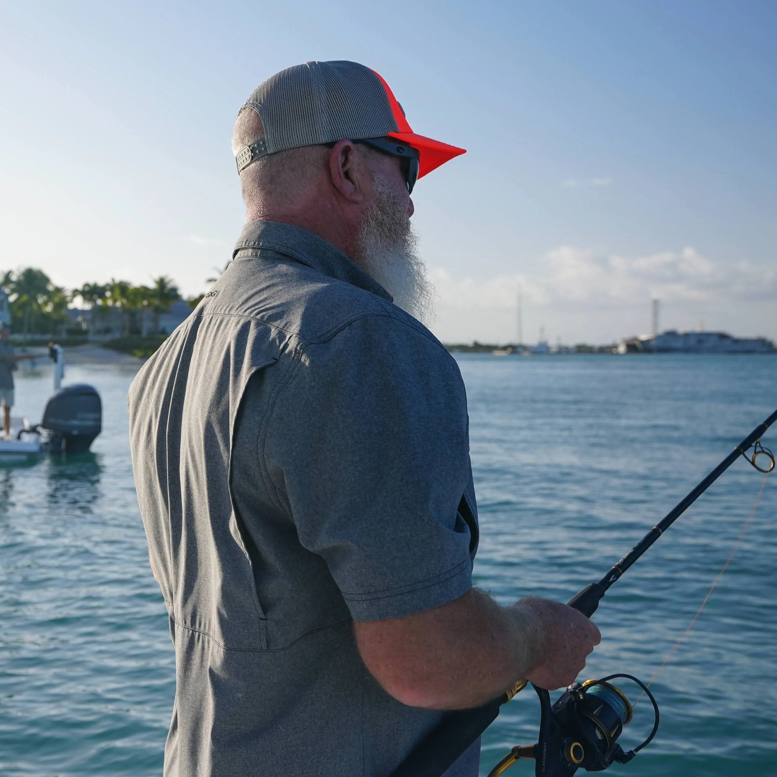 Man with a beard and sunglasses fishing on a boat