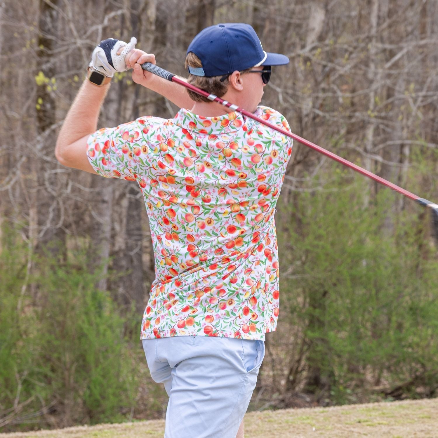 Person playing golf on a course with trees in the background