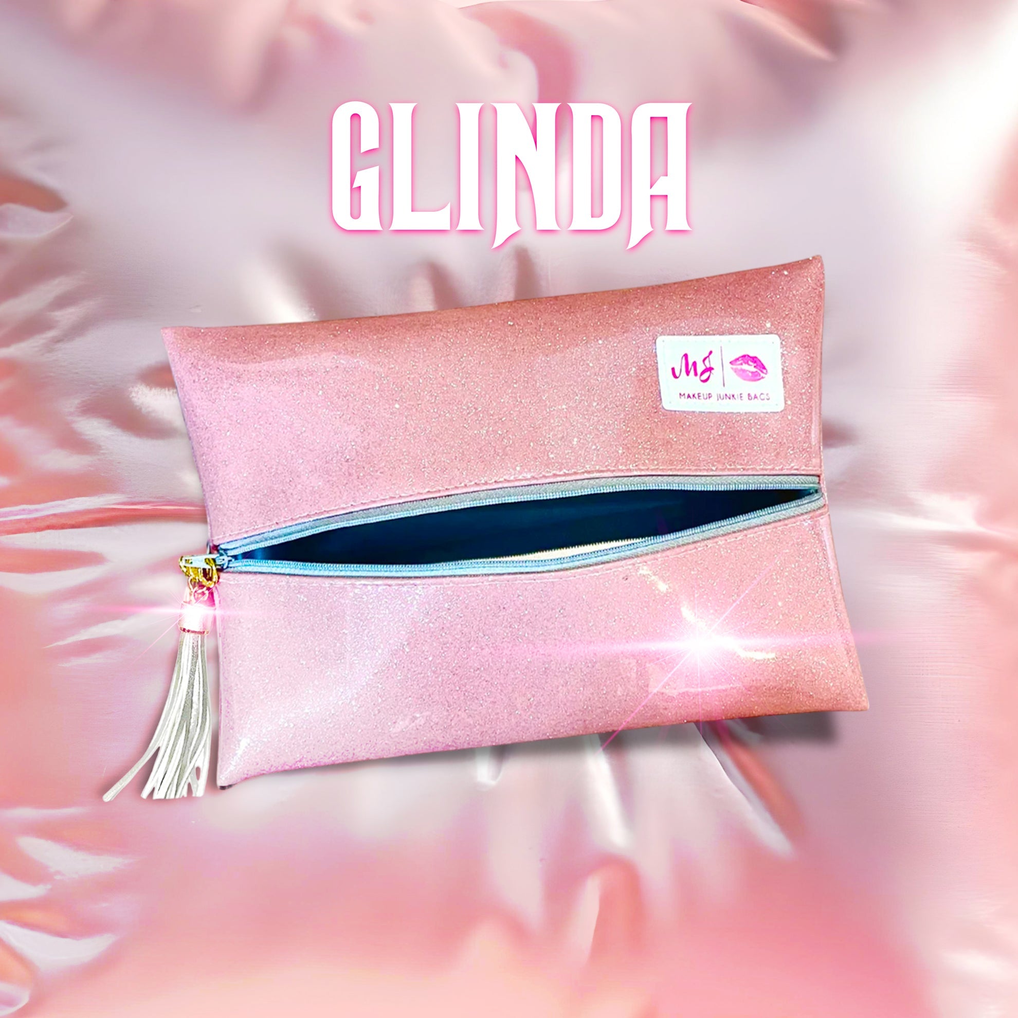 Pink glittery pouch with a blue interior and tassel on a pink and white fluffy background, featuring the brand 'GLINDA'.