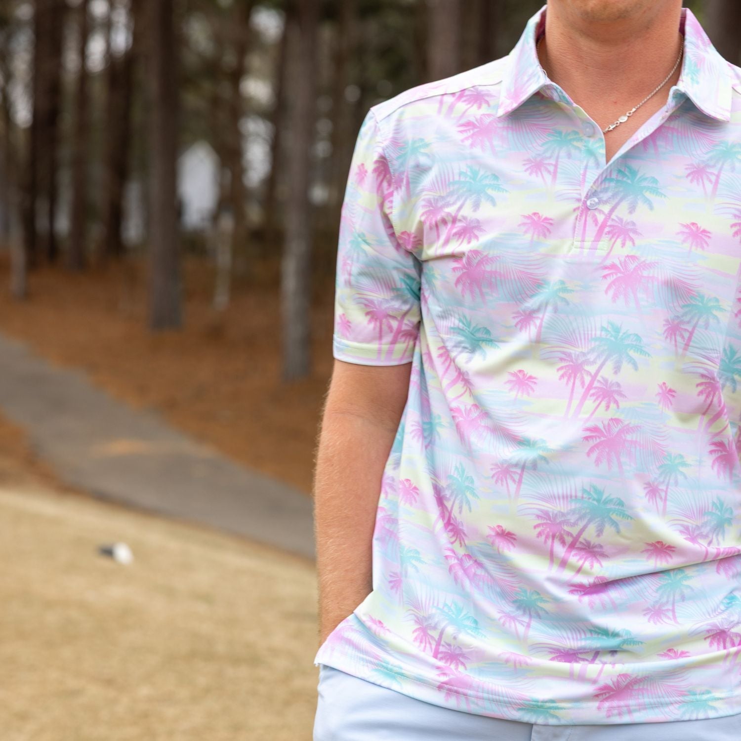 Person wearing a colorful palm tree patterned shirt in a golf course setting