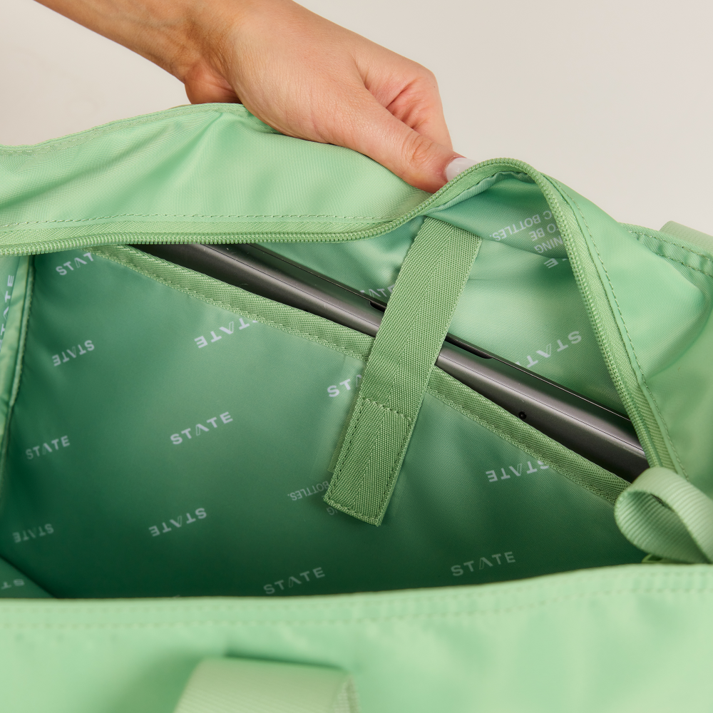 Green bag with 'STATE' branding being held open by a hand.
