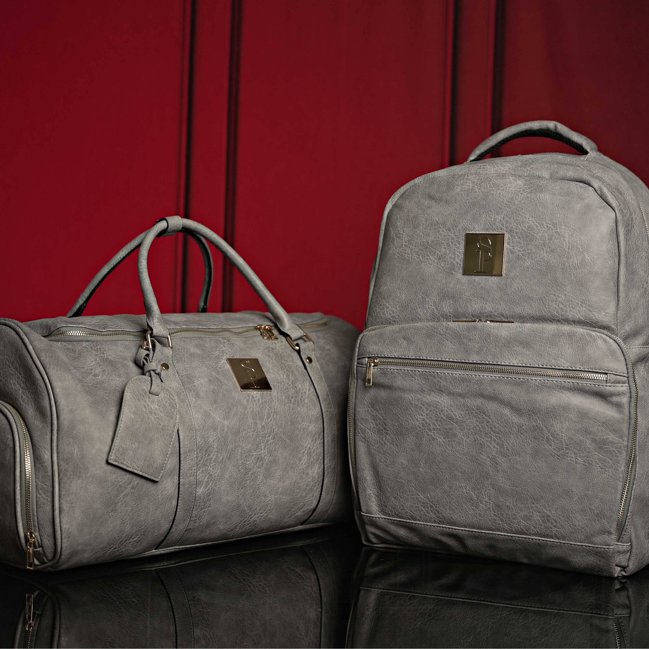 Gray duffel bag and backpack on a red background