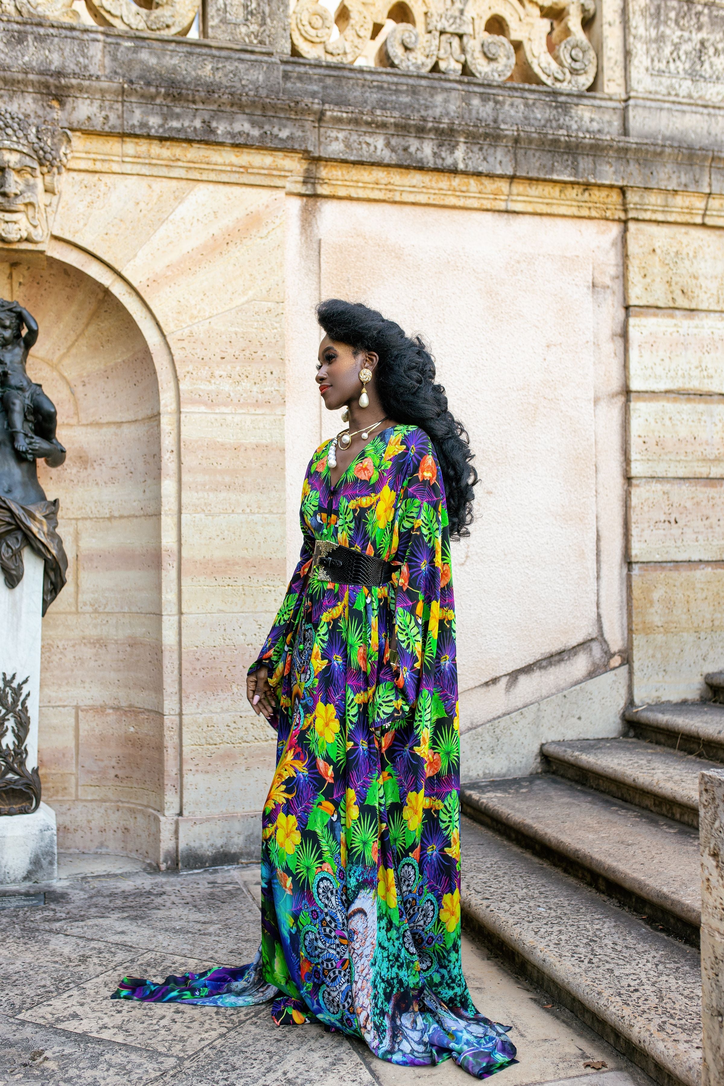 Woman in a colorful dress standing on stone steps with architectural background