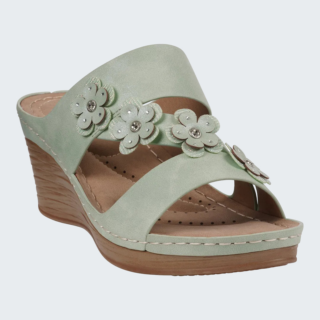 Light green wedge sandal with floral decorations on a white background