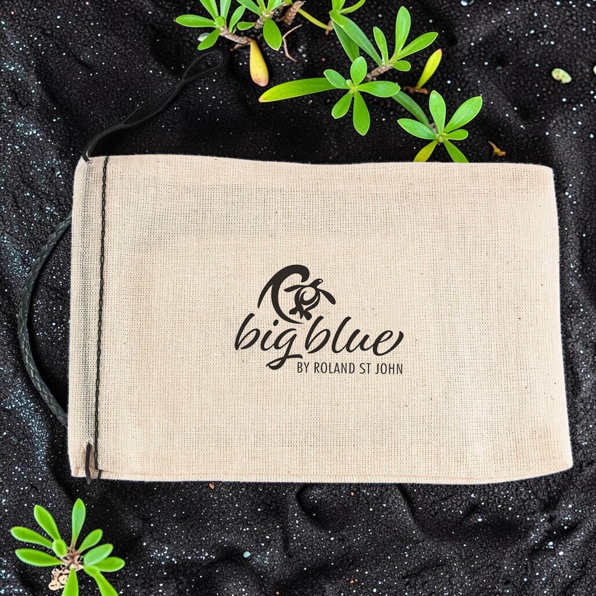 Beige pouch with 'bigblue' logo on a black textured background with green leaves.