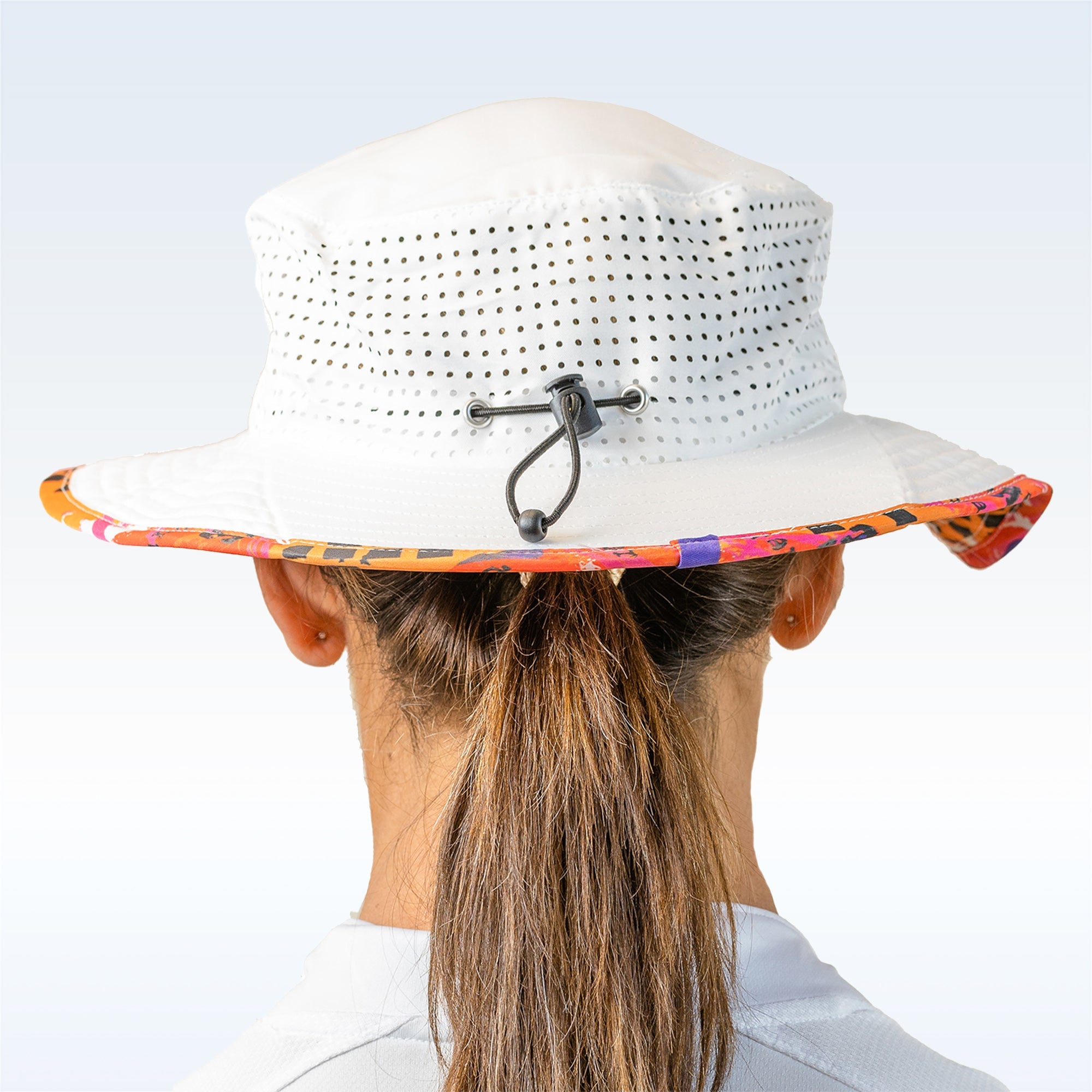 White sun hat with colorful band worn by a person on a light blue background