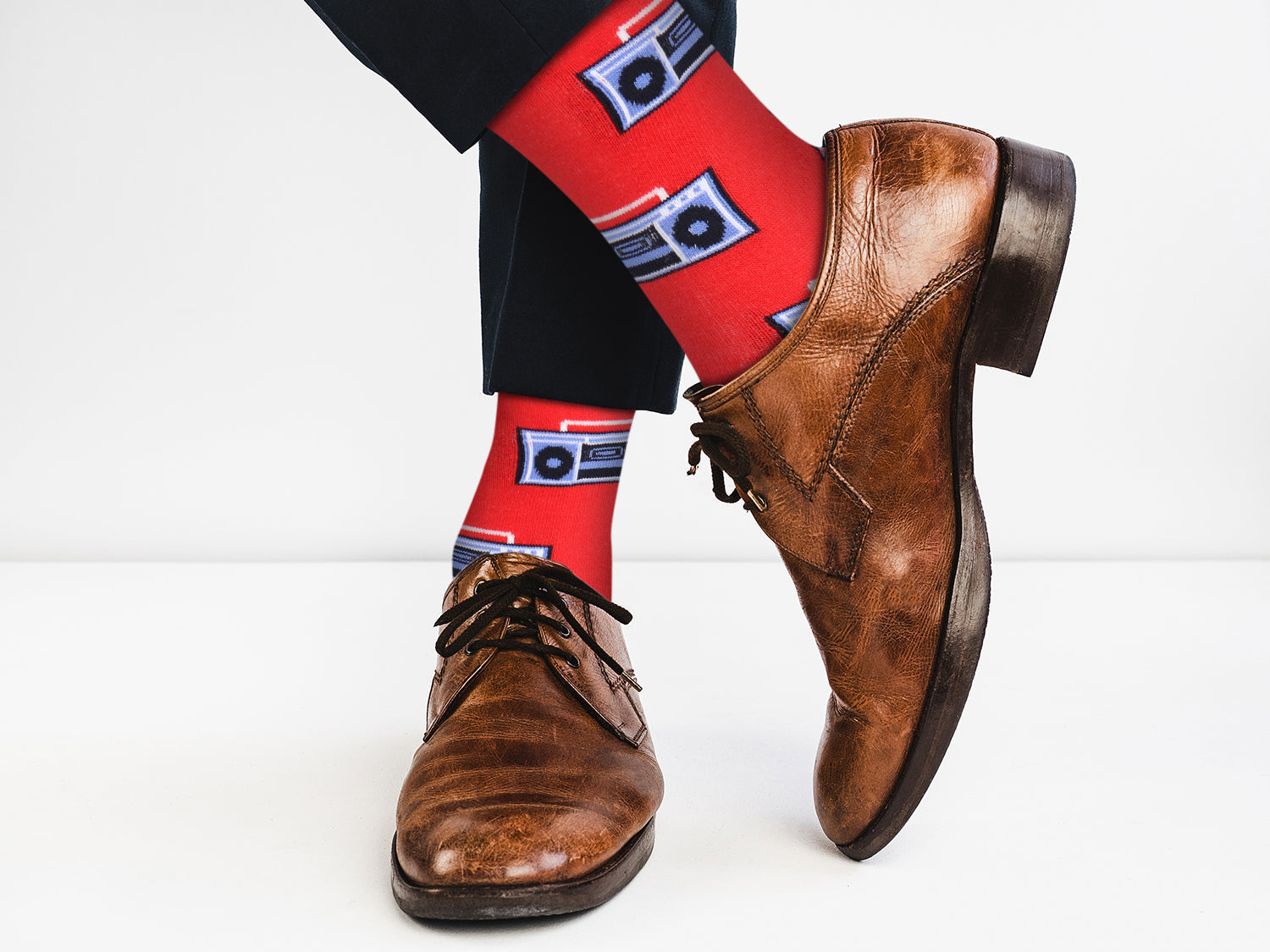 Brown leather shoes with red socks featuring cassette tape designs on a white background