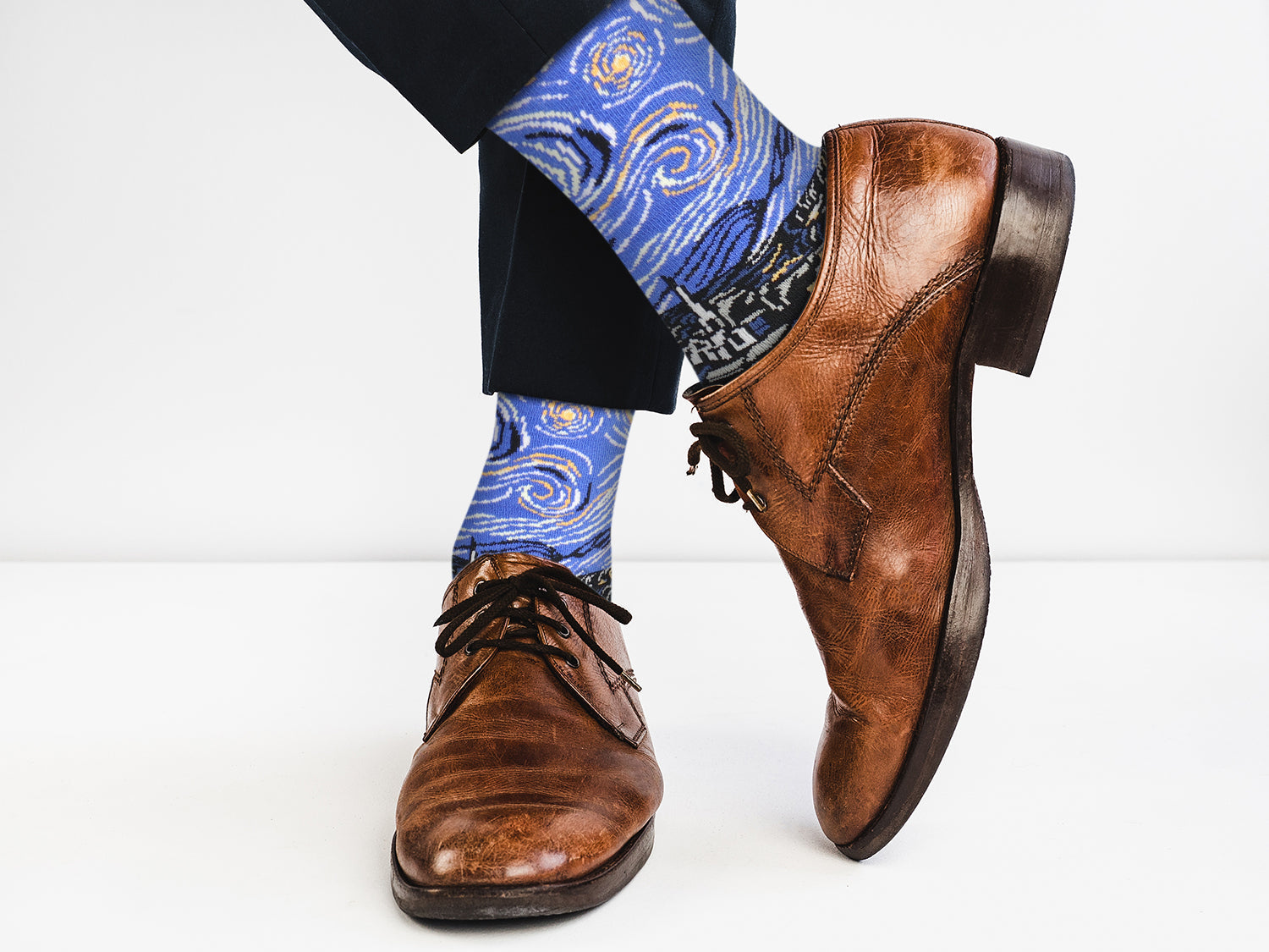 Brown dress shoes and blue socks with a pattern on a white background