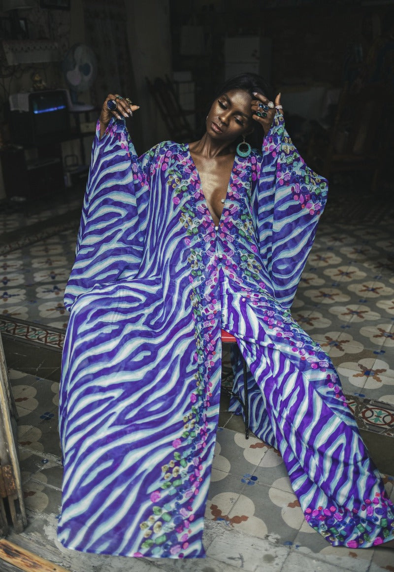 Person wearing a vibrant, patterned outfit with a zebra stripe design in a room with a tiled floor.