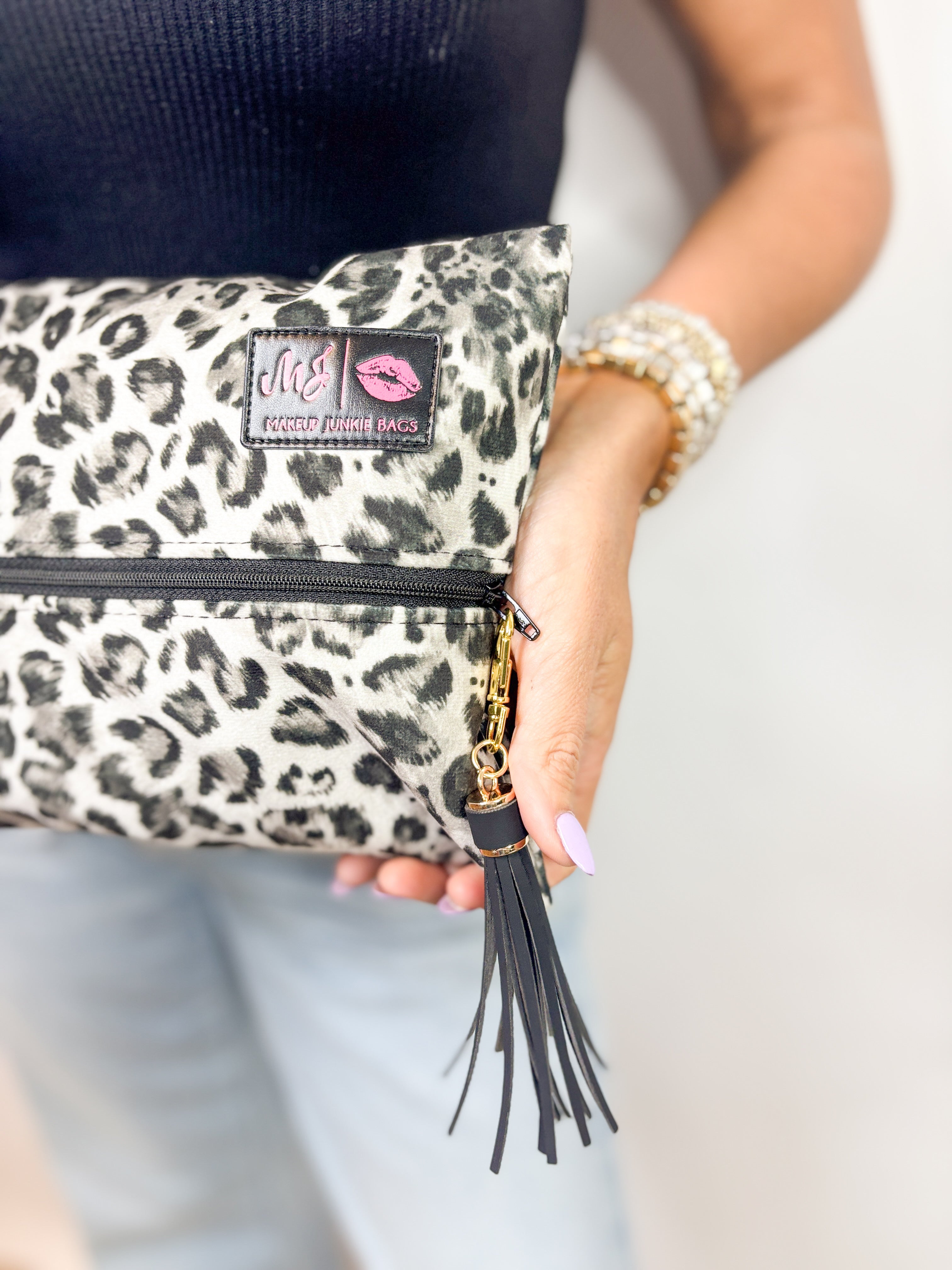 Leopard print pouch with a brand logo held by a person against a neutral background