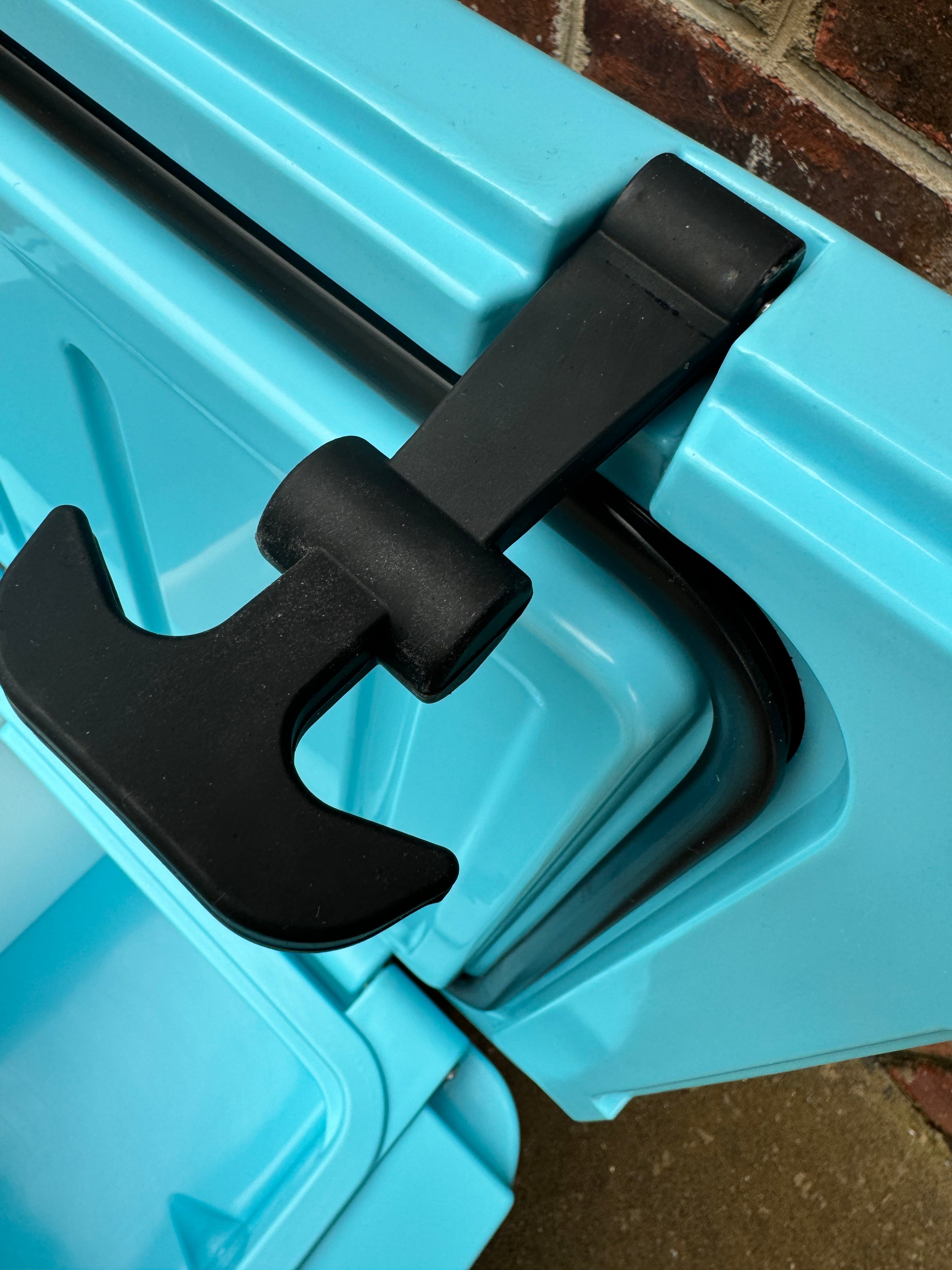 Close-up of a blue storage bin with a black handle on a brick surface.