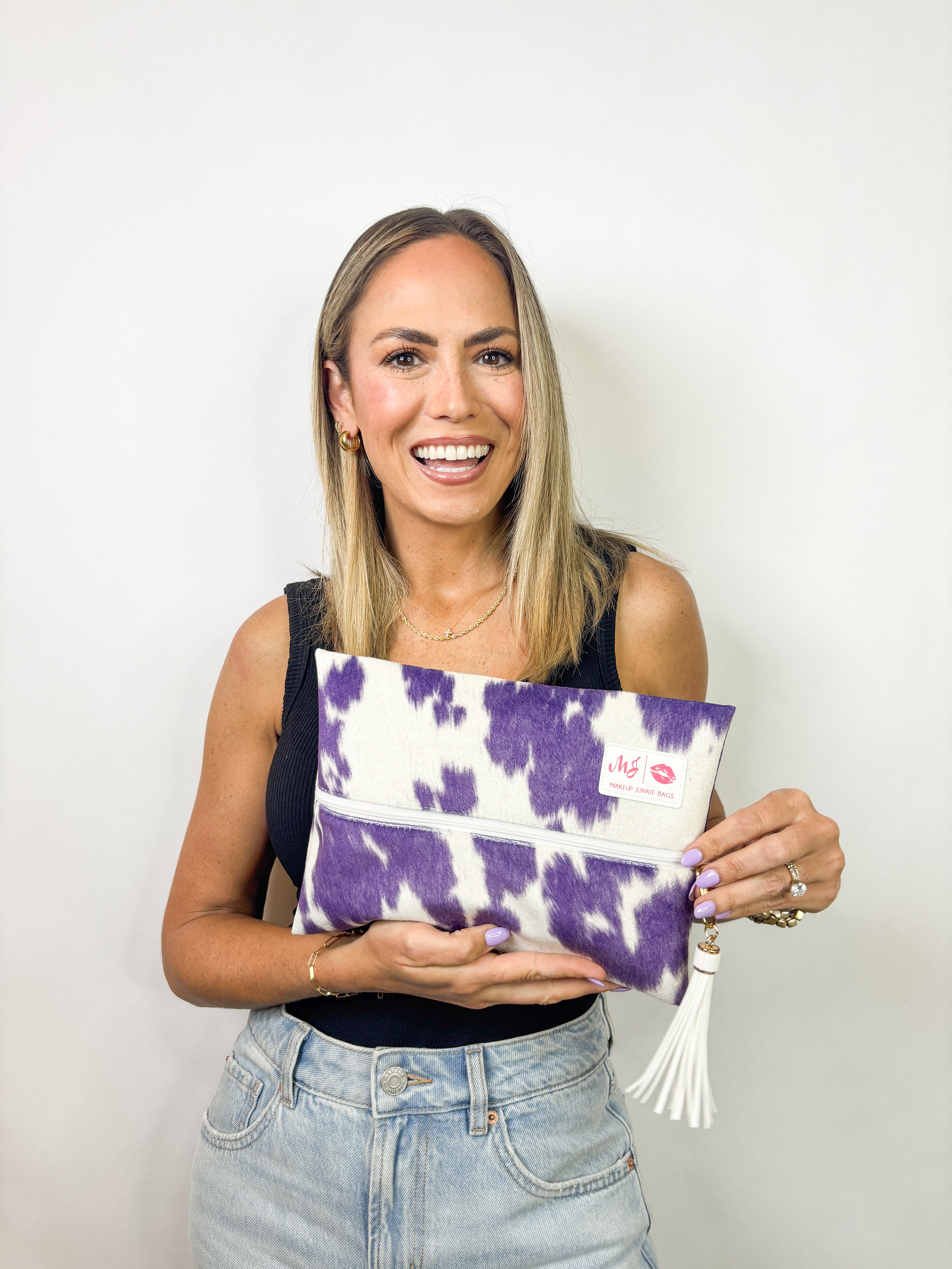 Woman holding a purple and white clutch against a plain background