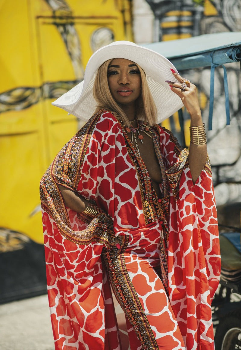 Woman wearing a red and white patterned dress with a wide-brimmed hat in an urban setting.