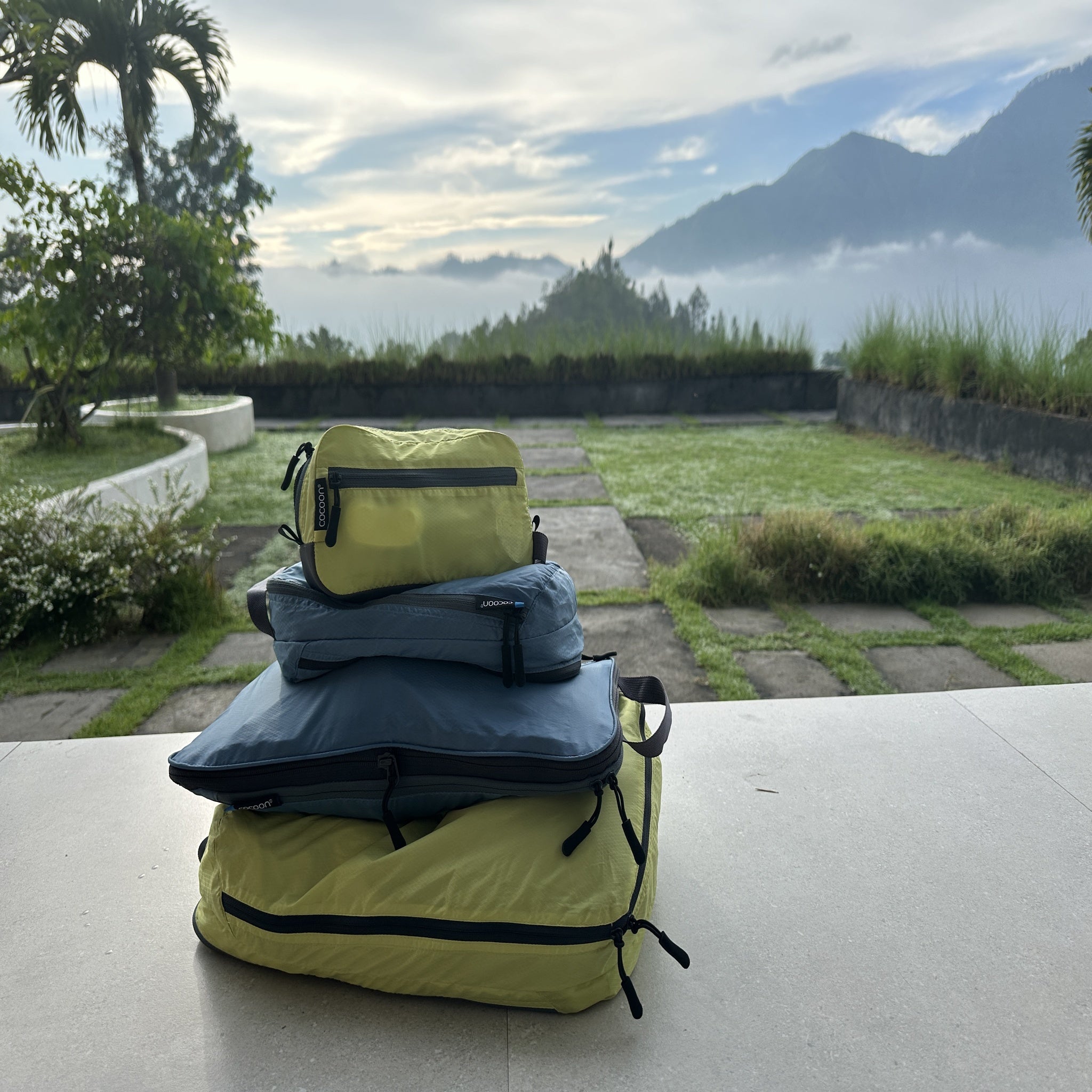Yellow backpack with clothes on a table with a scenic background of mountains and trees.