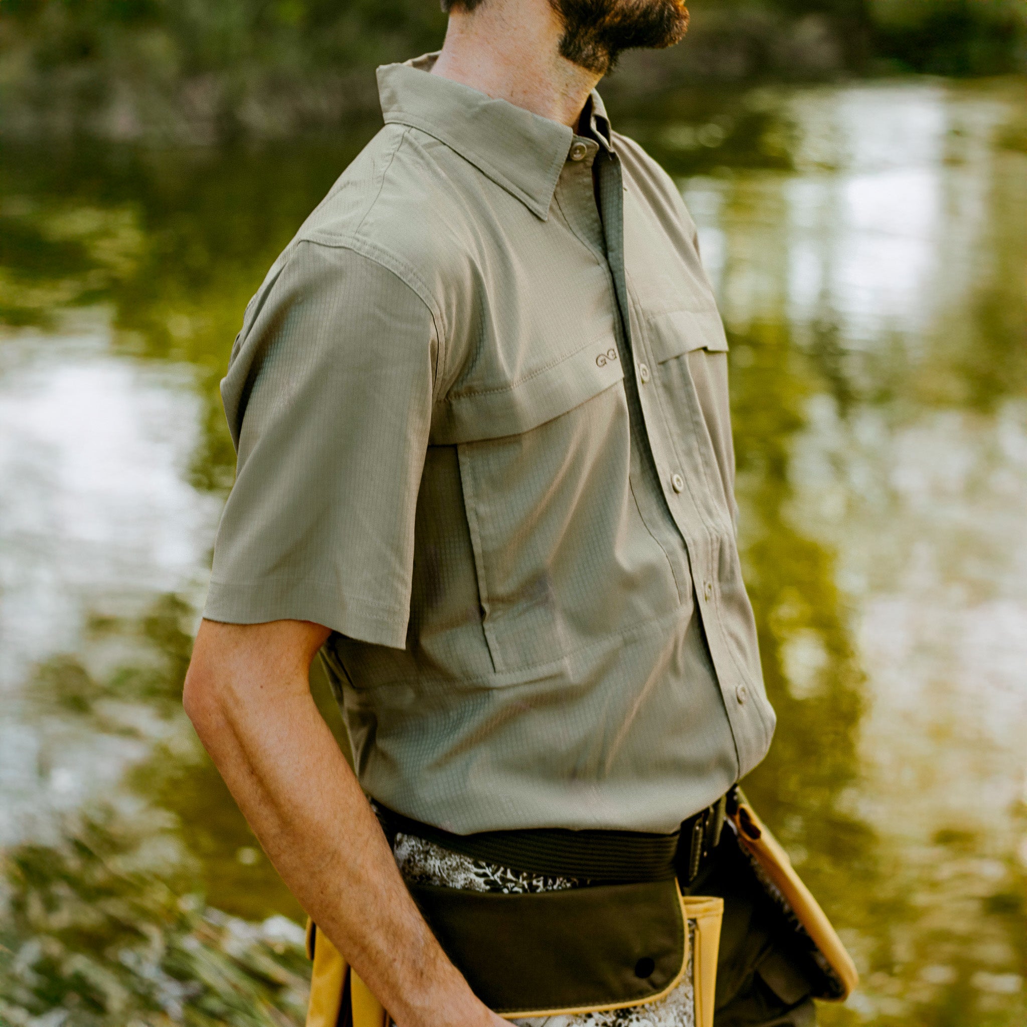 Person wearing a light brown shirt by a body of water