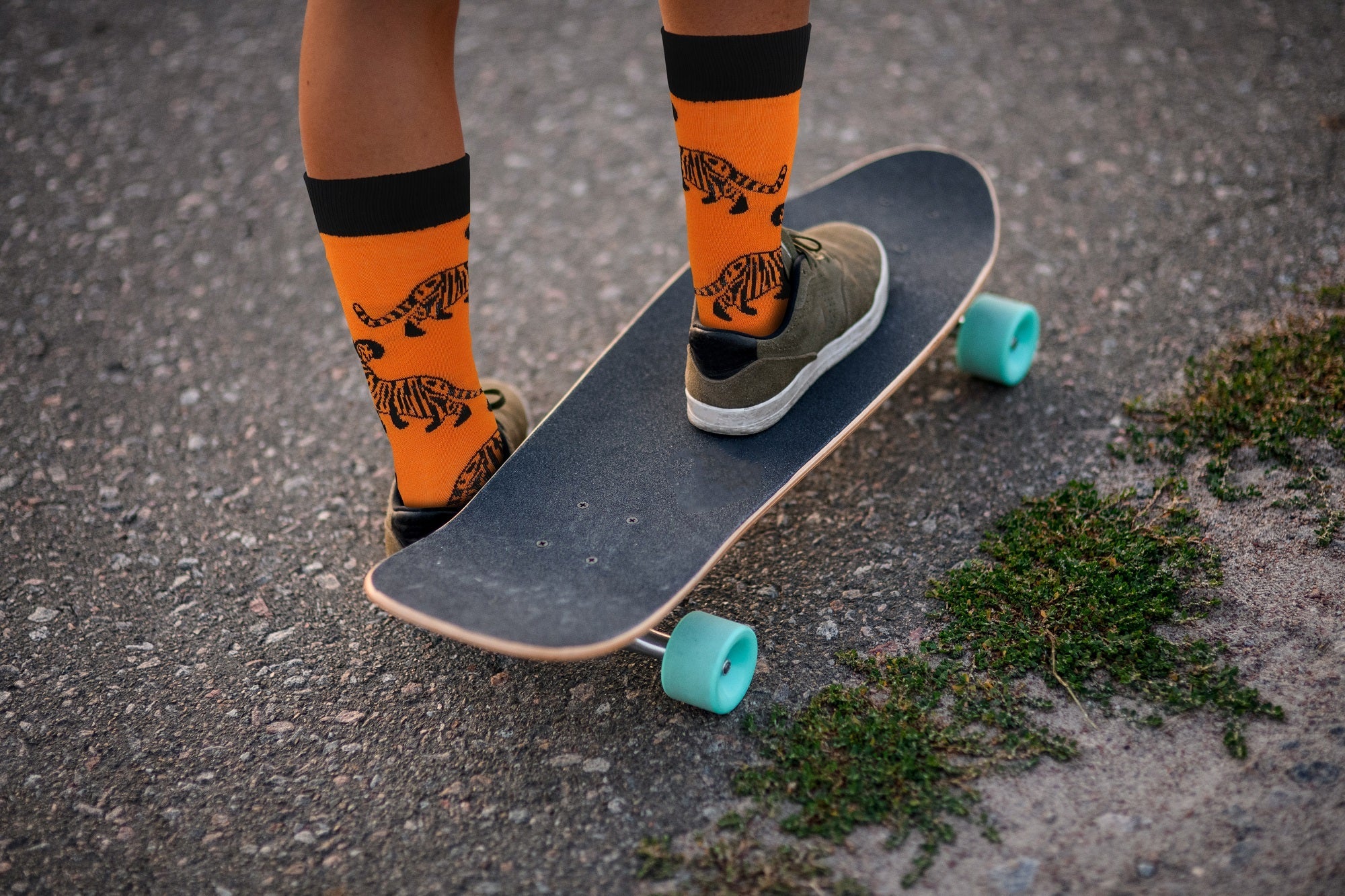 Person wearing orange socks with tiger design on a skateboard