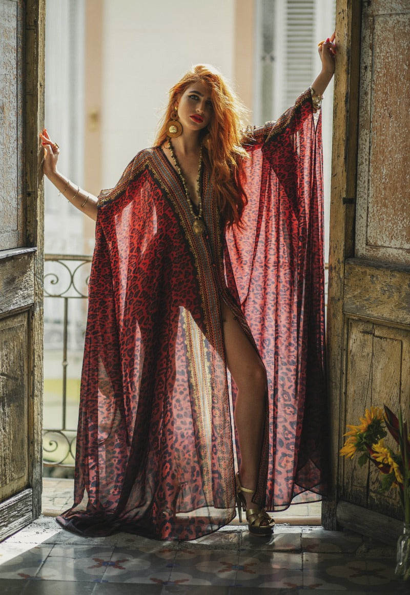 Woman in a long, patterned dress standing in a doorway with sunlight streaming in.