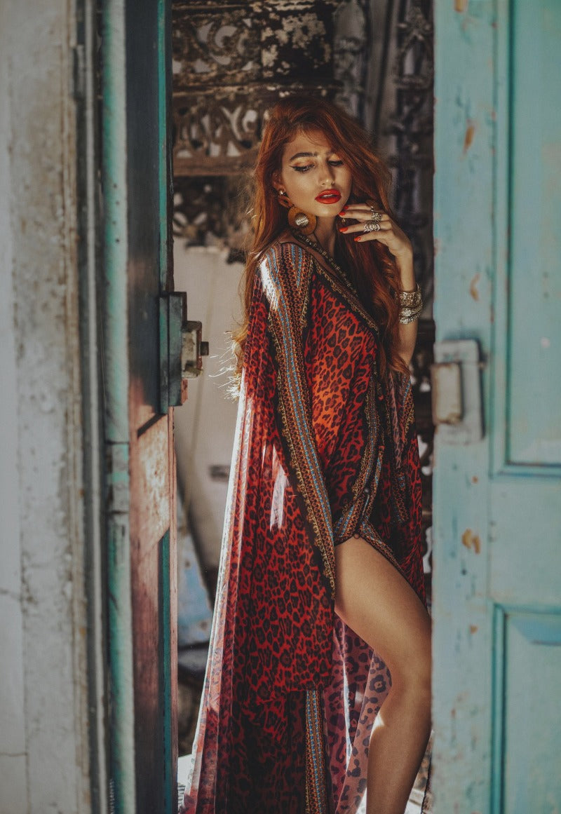 Woman in a patterned dress standing in front of a textured wall and turquoise door.
