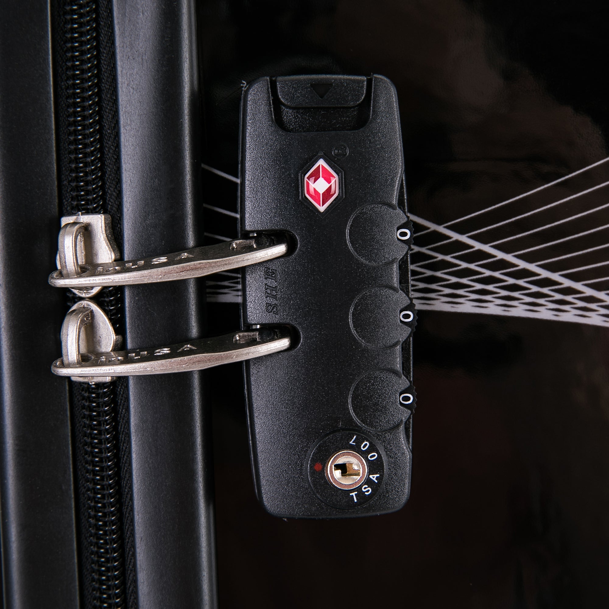 Close-up of a black suitcase lock with a red logo on a dark background