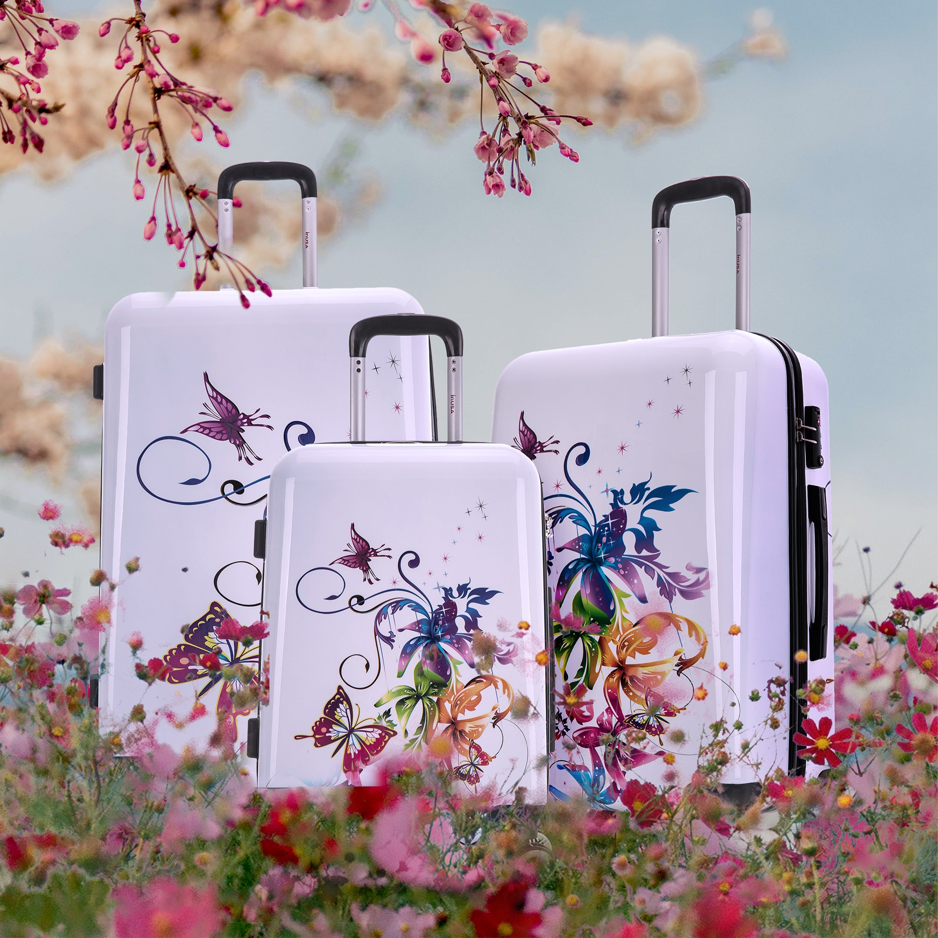 Set of white suitcases with butterfly designs in a floral outdoor setting