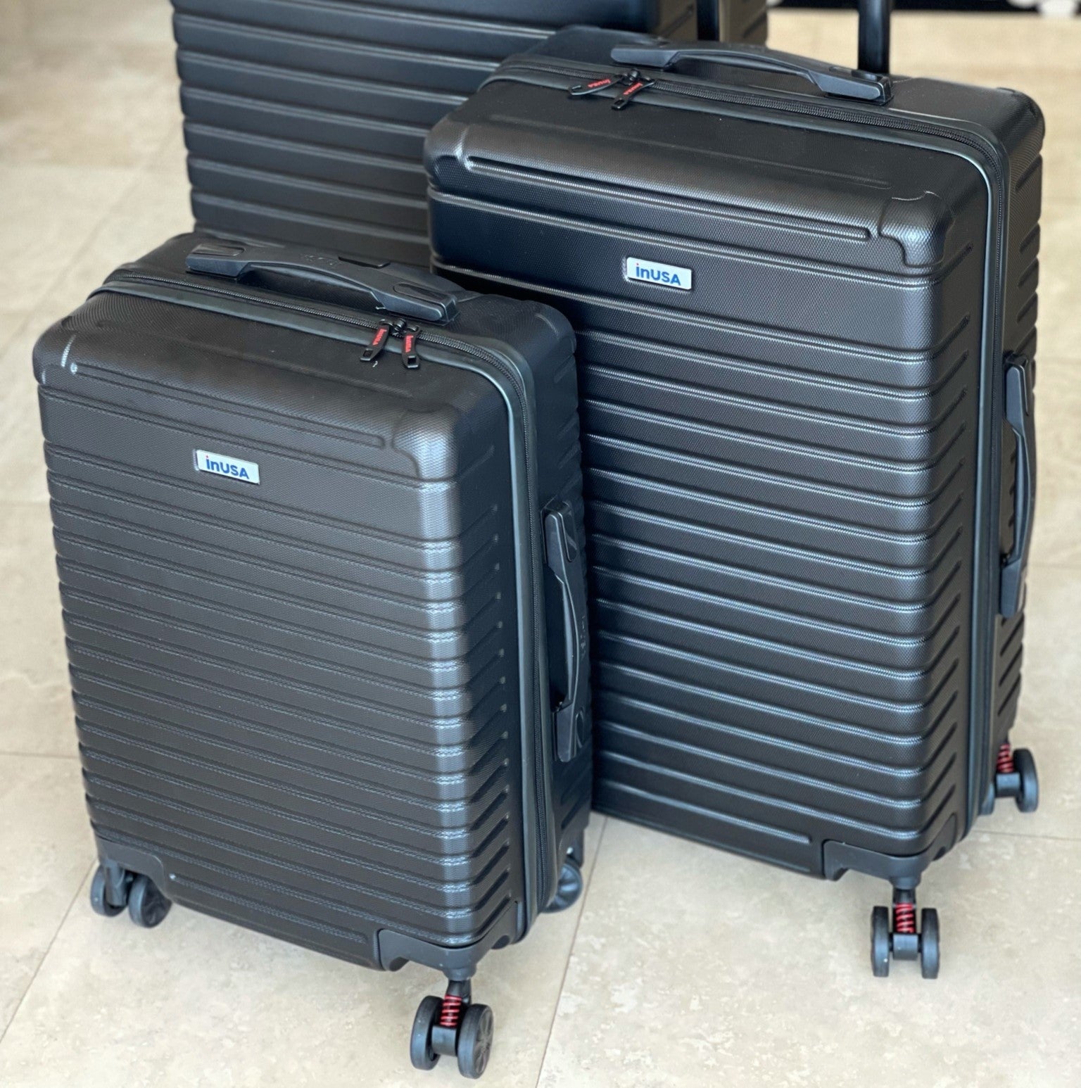 Three black suitcases with visible 'Husa' branding on a light-colored floor.
