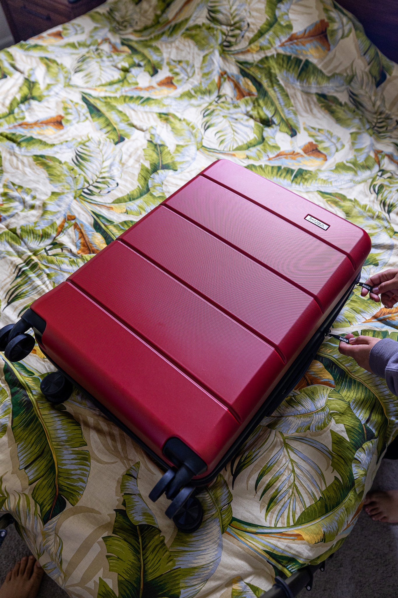 Red suitcase on a bed with a floral pattern