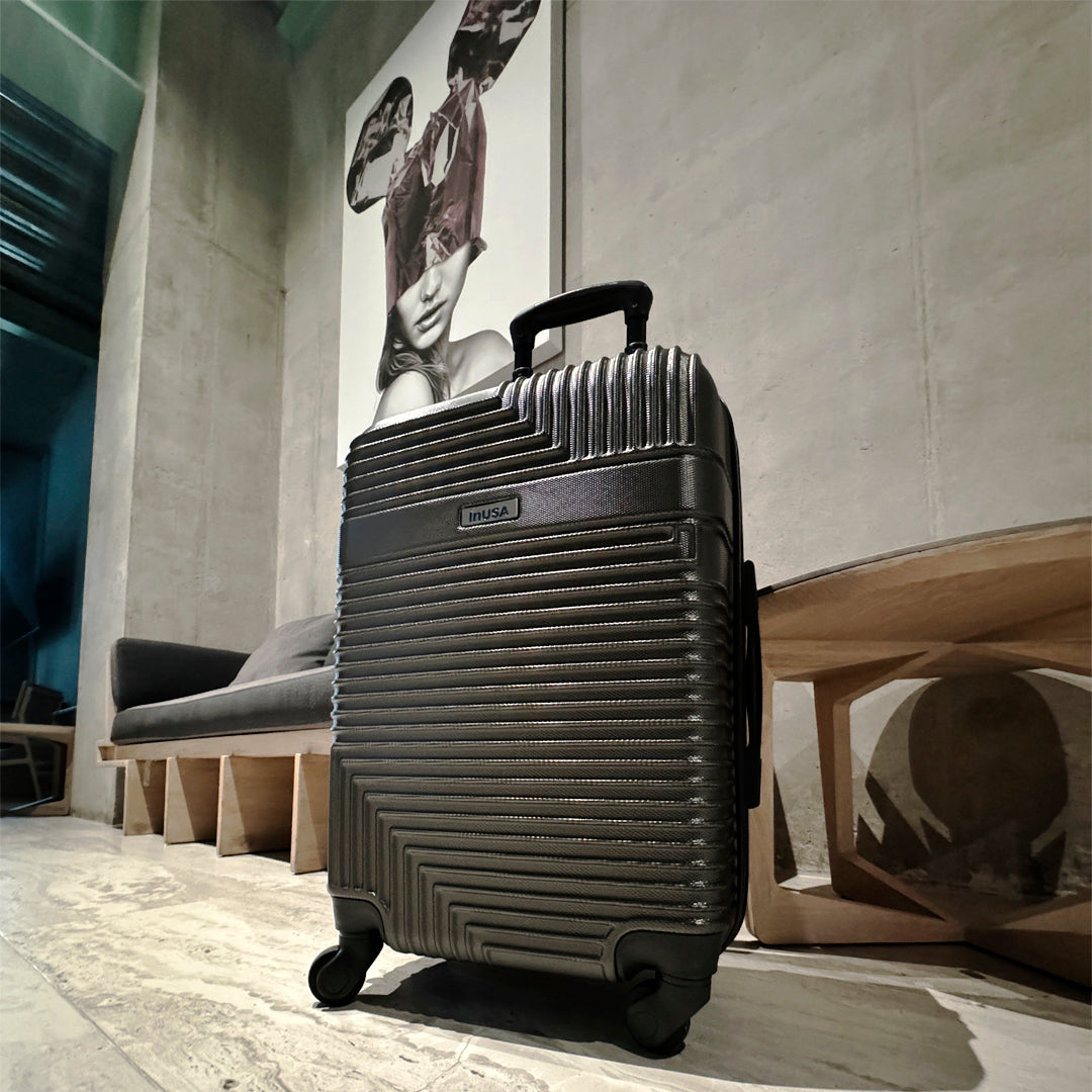 Black suitcase on wheels in a modern interior setting with a large abstract painting on the wall.