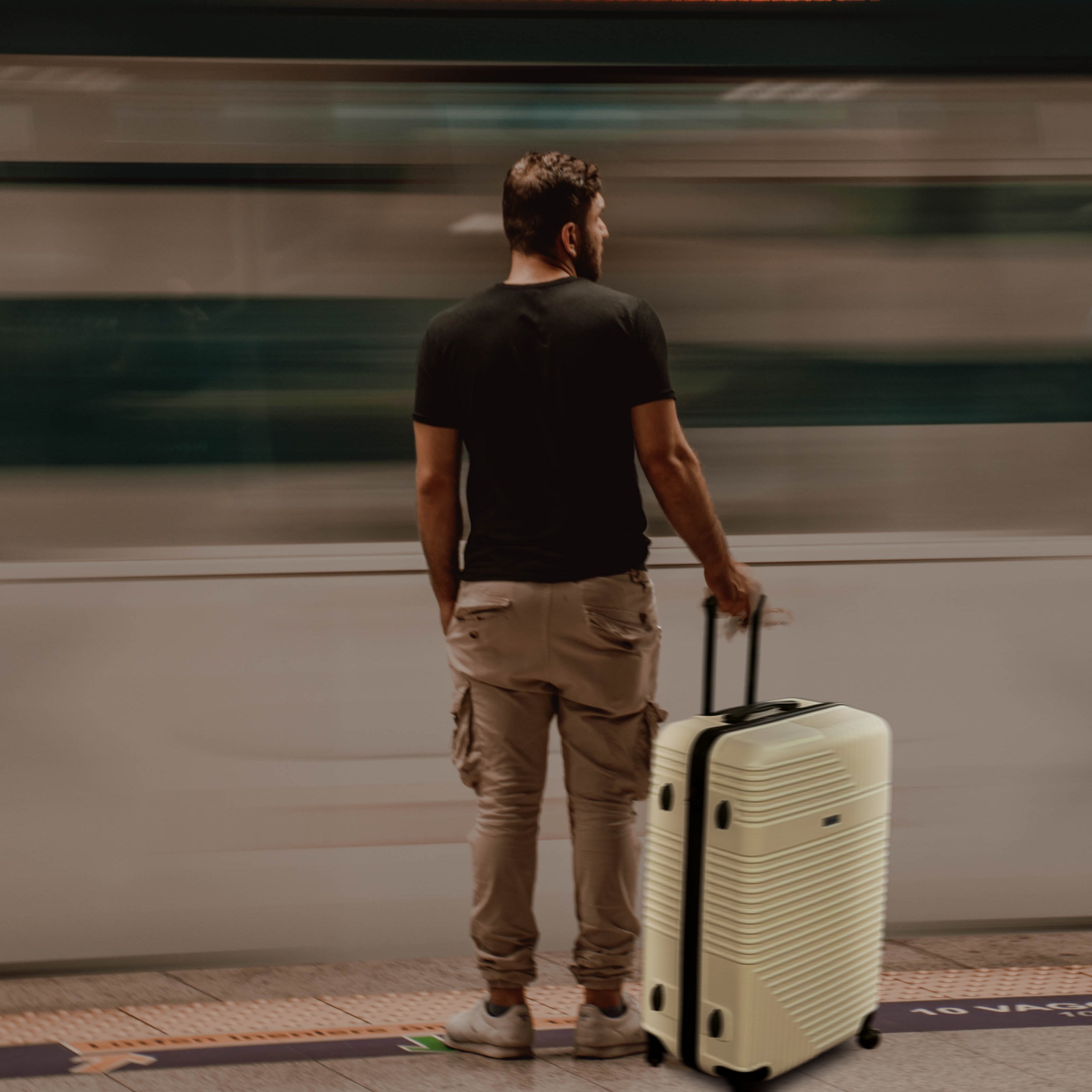 Man with a suitcase standing on a platform as a train passes by