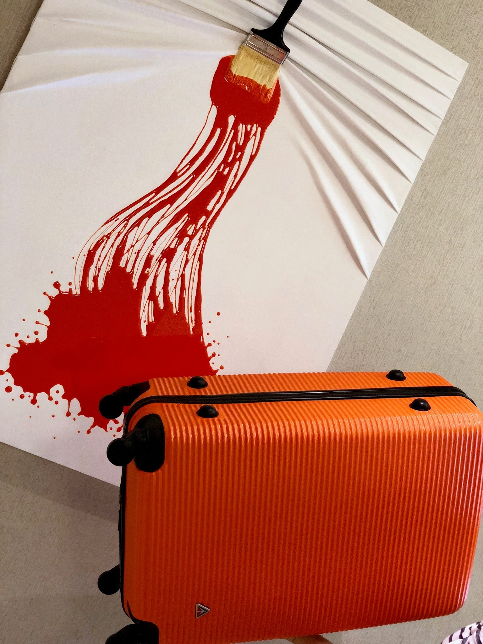 Orange suitcase with a red paint splatter on a white background