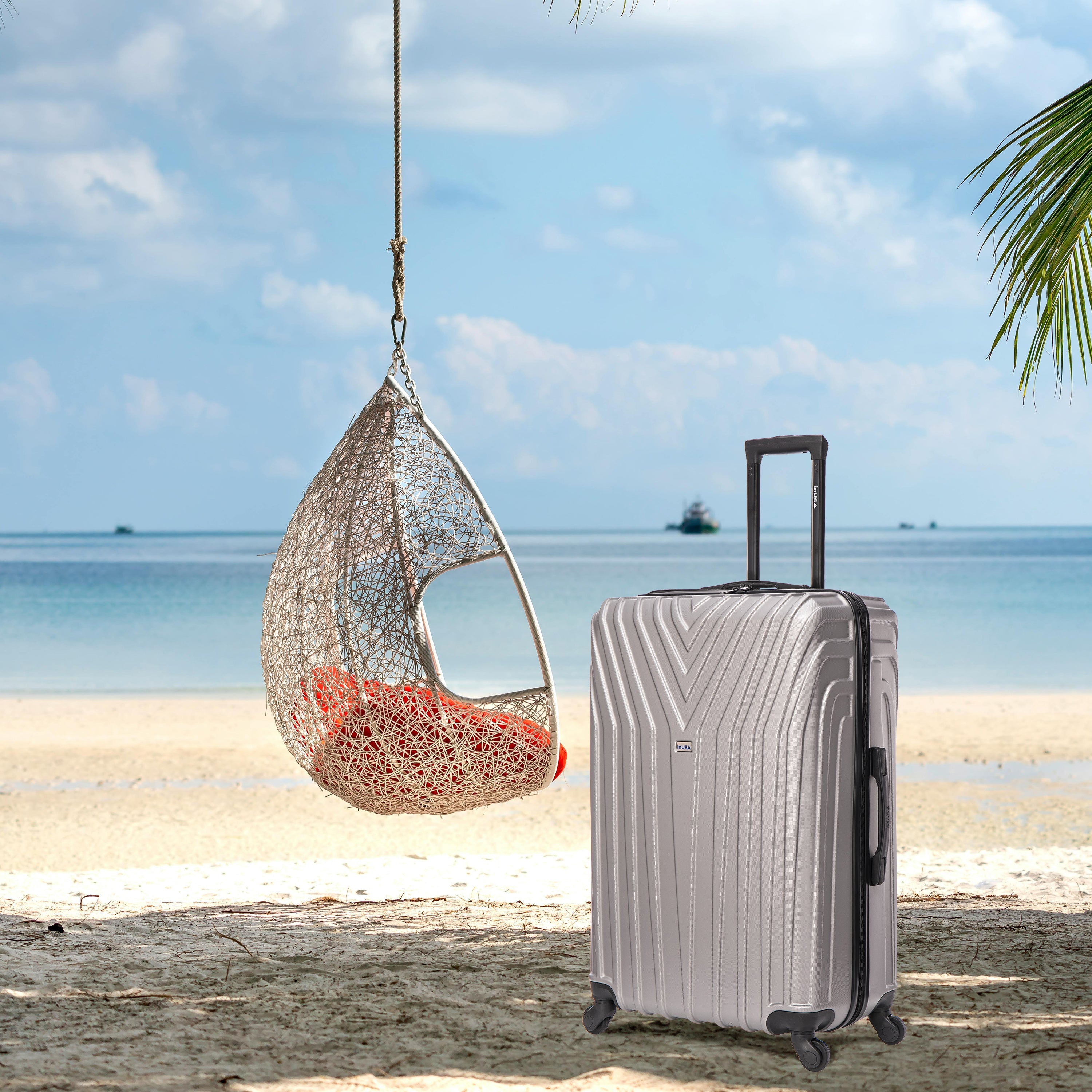 Suitcase next to a hanging chair on a beach with ocean view