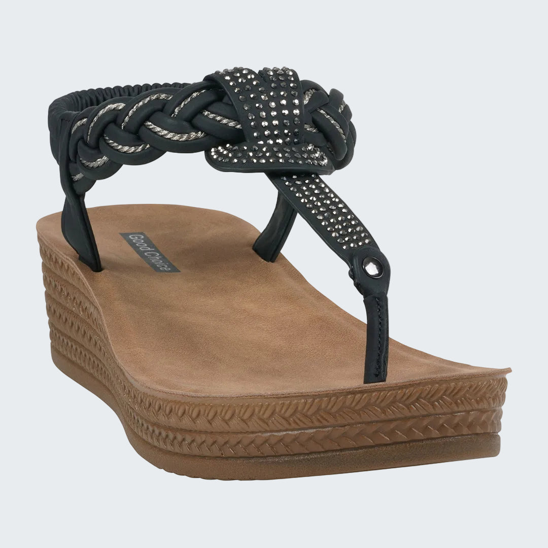 Brown wedge sandal with black braided strap on a white background