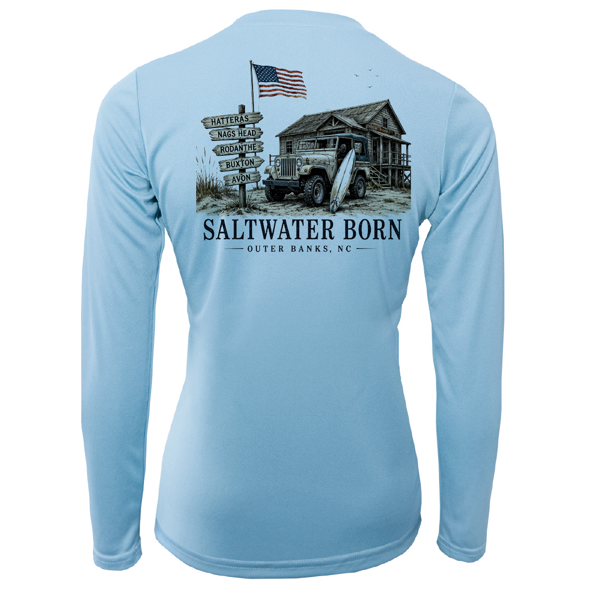 A light blue long-sleeve performance shirt shown from the back, featuring a large graphic print of a rustic cabin, vintage truck, surfboard, signpost, and an American flag with the text 'SALTWATER BORN OUTER BANKS, NC'.
