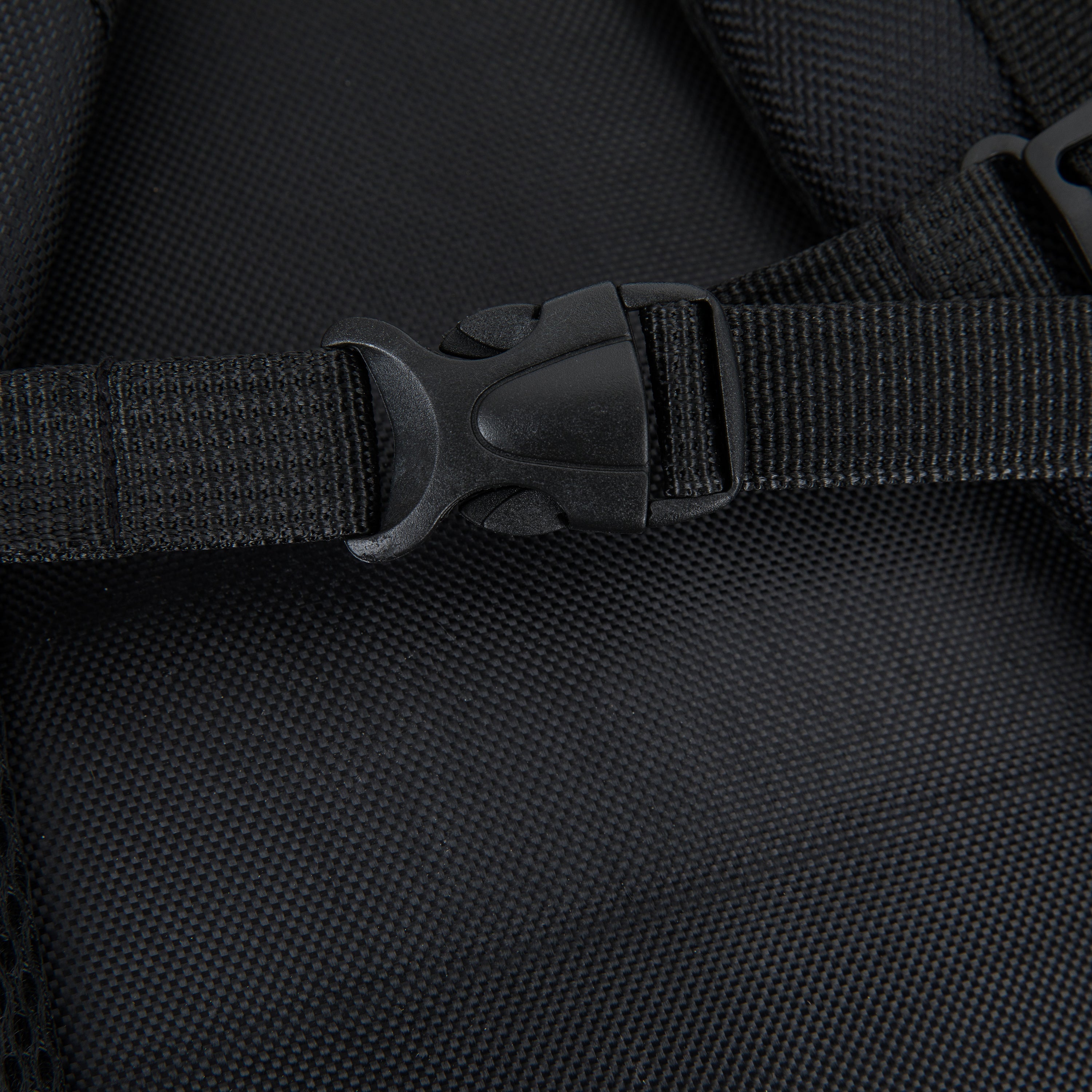 Close-up of a black backpack strap with buckle on a black background