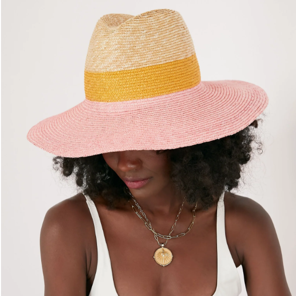 Woman wearing a pink and yellow straw hat on a white background