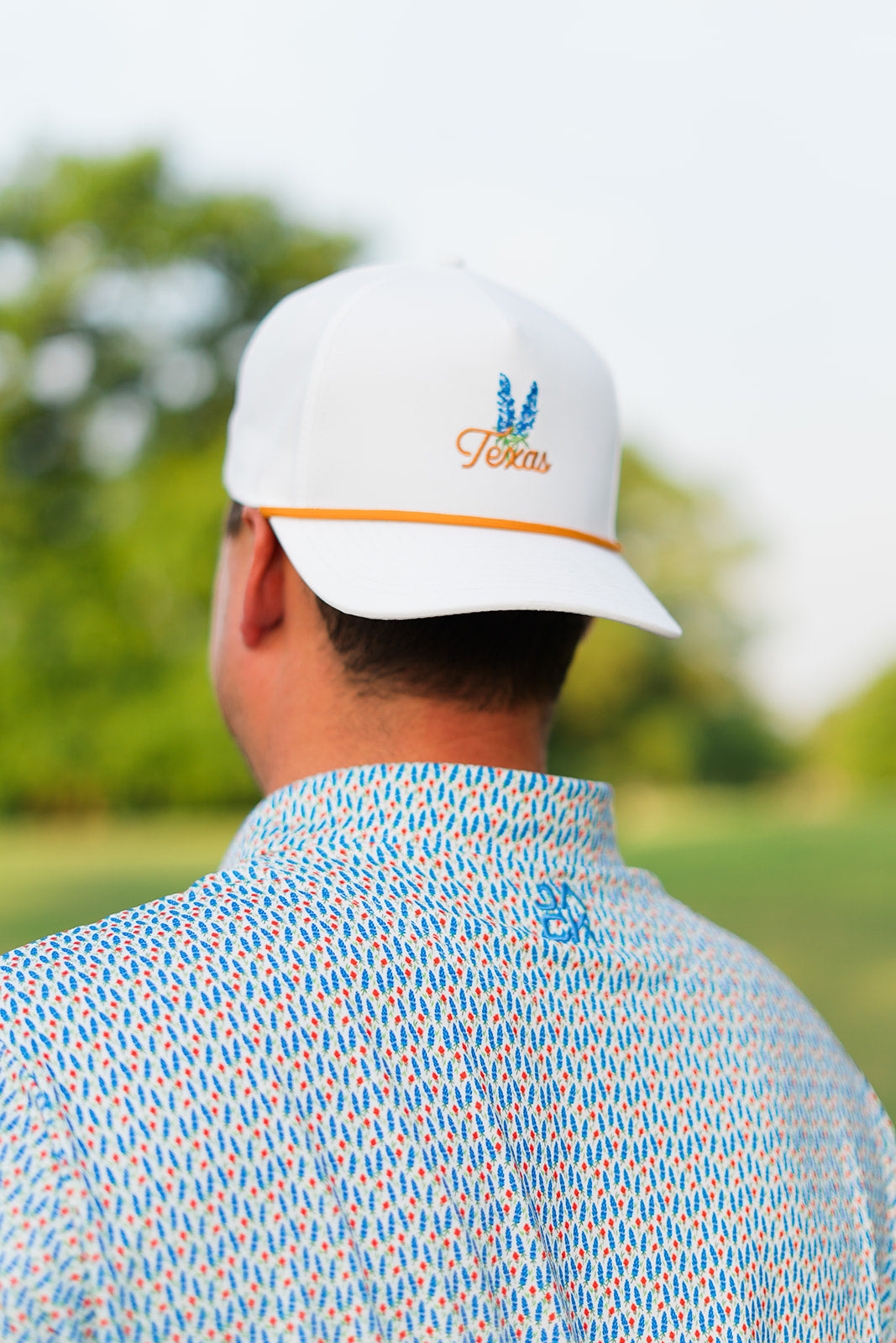 Person wearing a white cap with branding in an outdoor setting